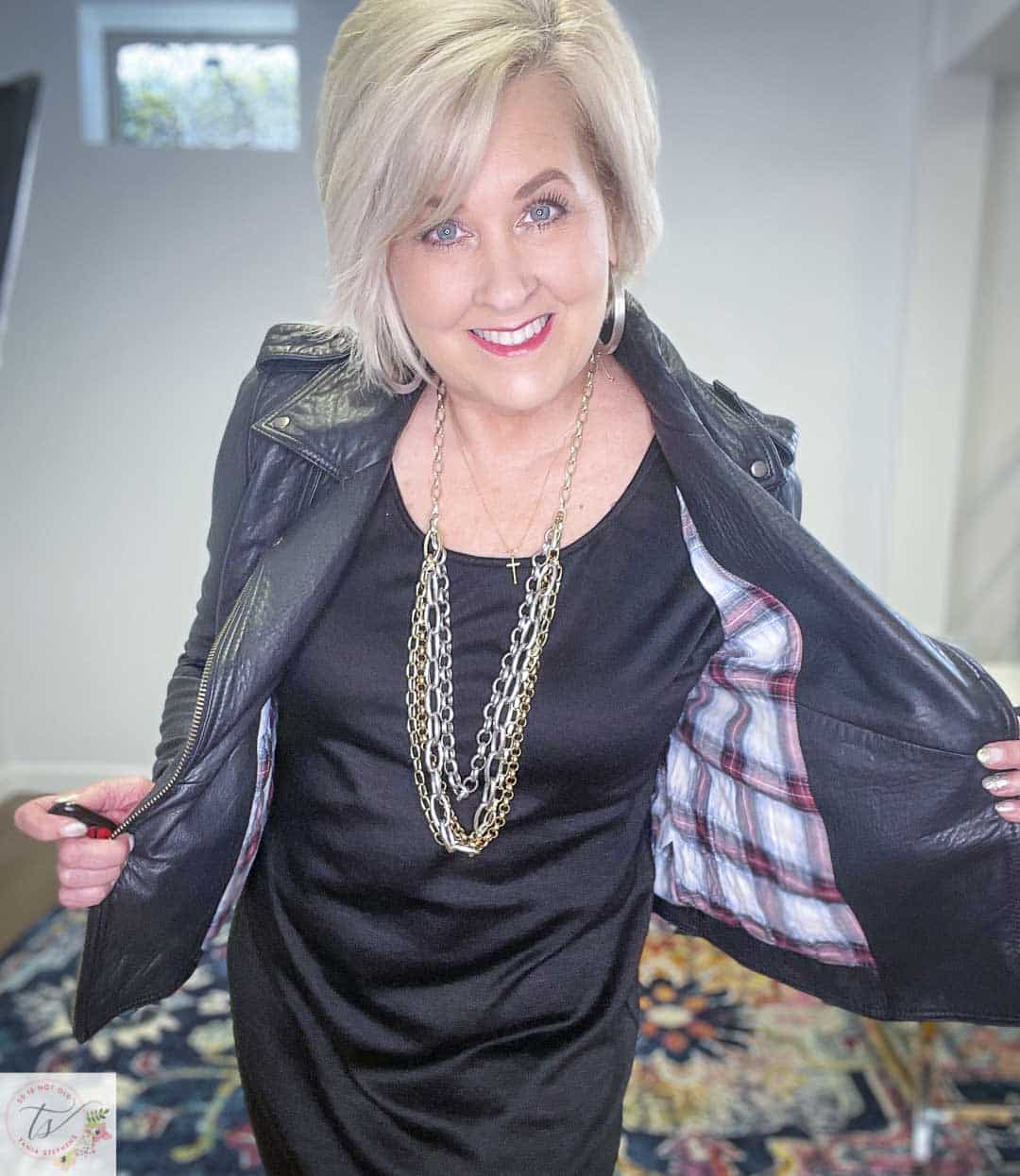 Over 40 Fashion Blogger, Tania Stephens, is wearing a little black dress and showing the lining of a black leather moto jacket