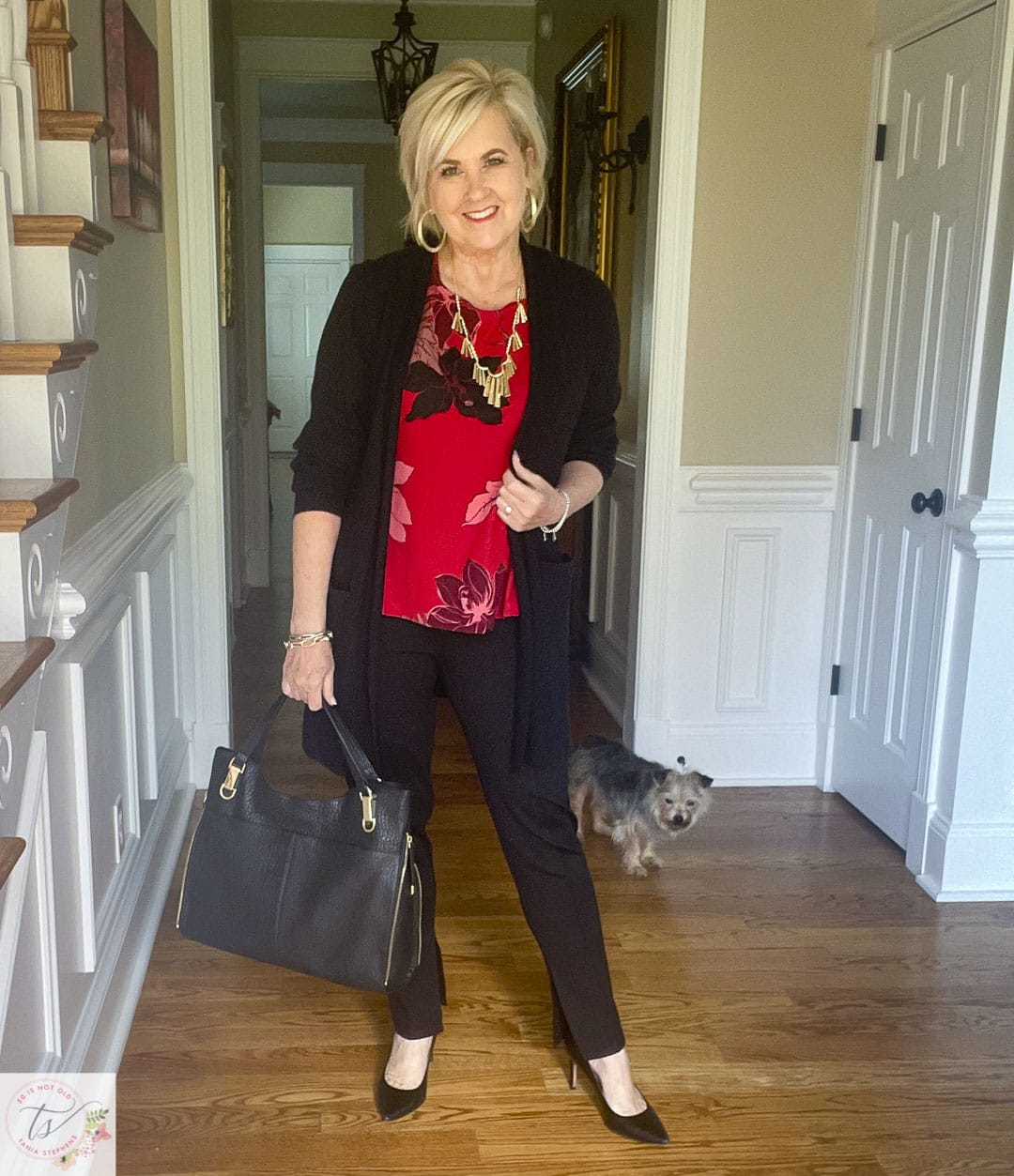 Over 40 Fashion Blogger, Tania Stephens is ready for a fall wedding wearing this off a red and black floral top, a black cardigan, gold jewelry, and black side split pants