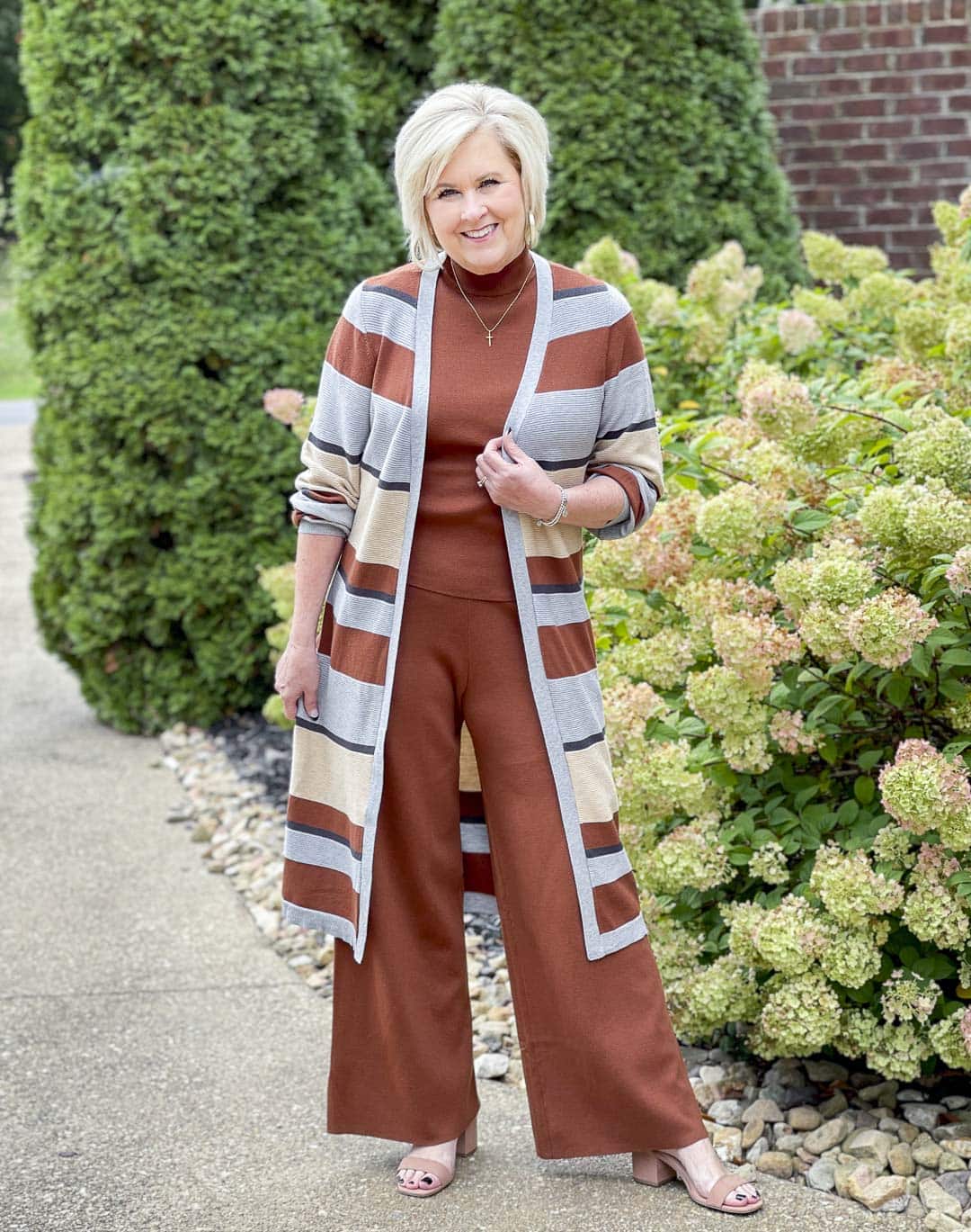 Over 40 fashion blogger, Tania Stephens, is wearing a striped cardigan with a dark rust sweater tank and pants perfect for Thanksgiving Dinner