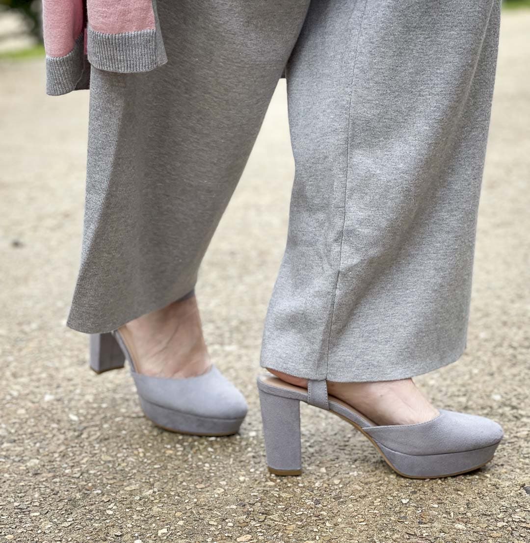 Over 40 fashion blogger, Tania Stephens, is standing by hydrangeas wearing gray sweater pants with gray platform shoes