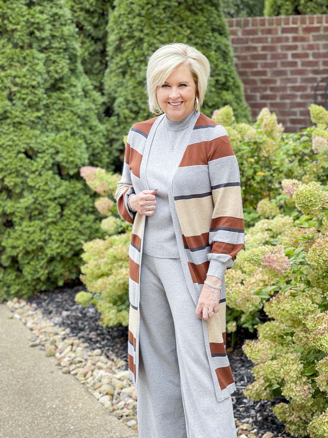 Over 40 fashion blogger, Tania Stephens, is wearing a striped cardigan with a gray sweater tank and pants that would be perfect for Thanksgiving Dinner