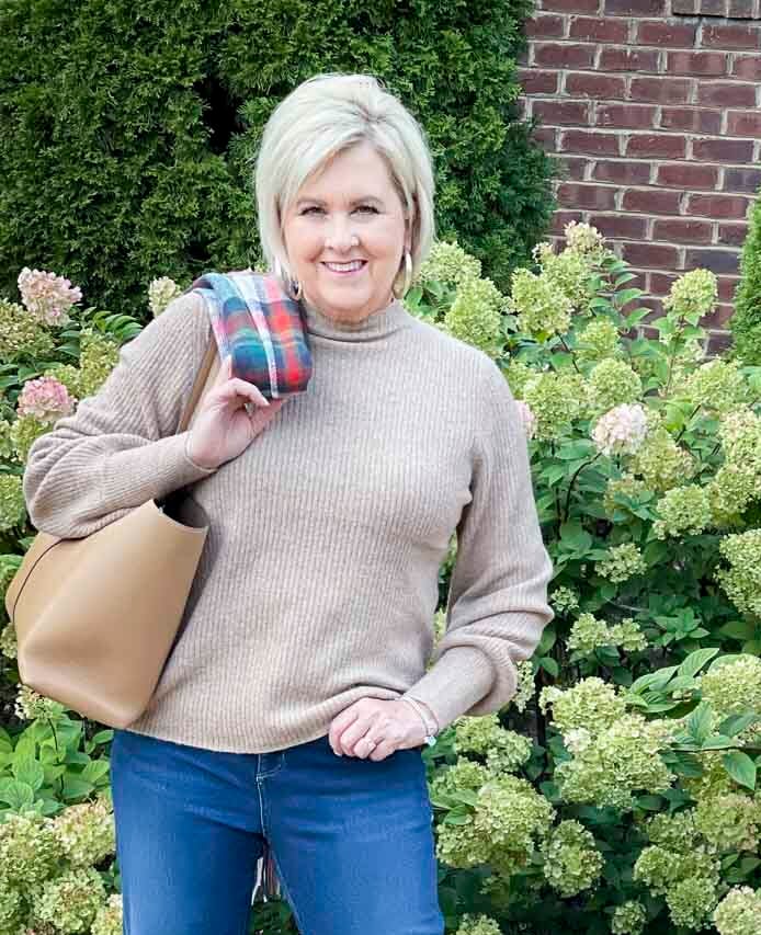 Over 40 Fashion Blogger, Tania Stephens, is wearing a ribbed mock neck sweater with a camel tote