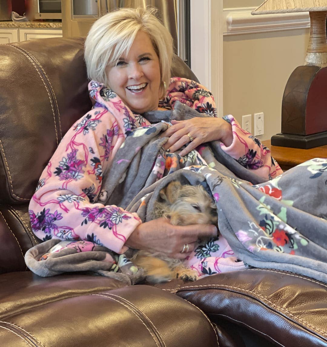 Over 40 fashion blogger, Tania Stephens is staying warm on cold rainy mornings in a robe from Vera Bradley in the Hope Blooms Pink print and sitting with her dog who is under a Hope Blooms throw blanket