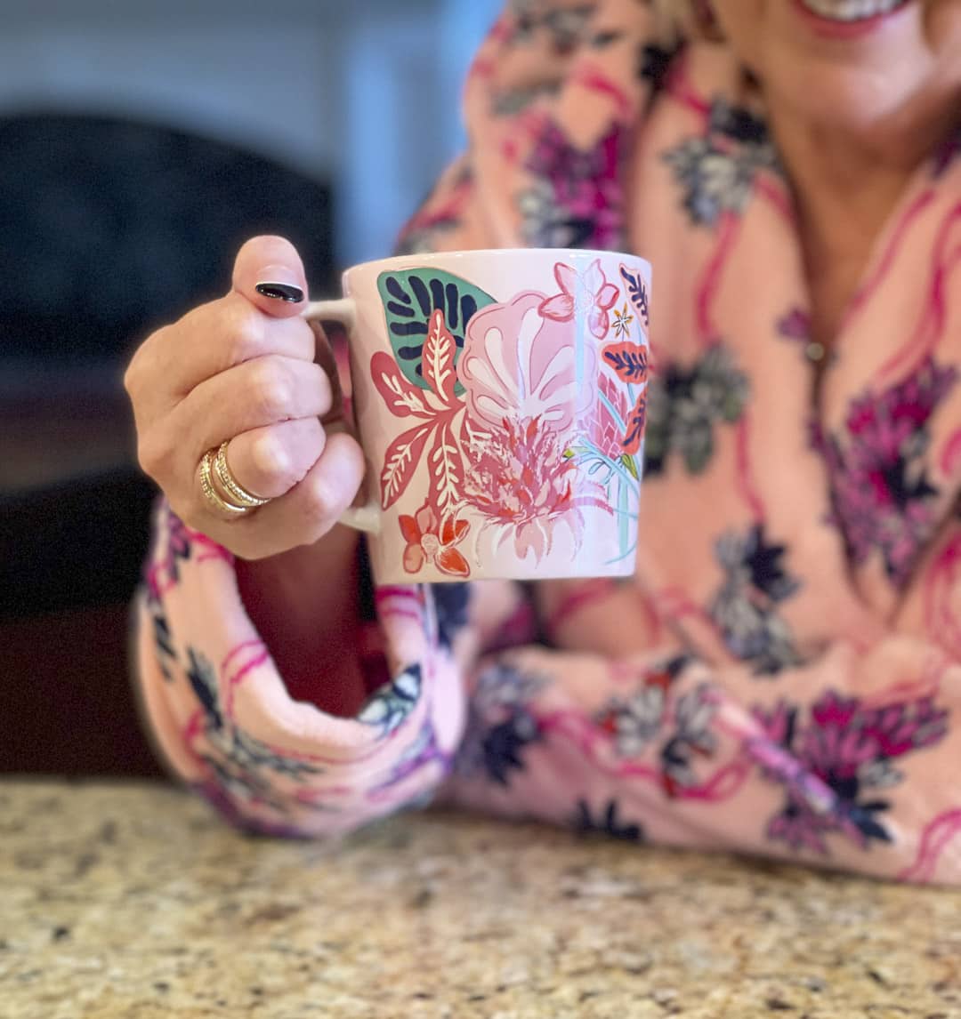 Over 40 fashion blogger, Tania Stephens is staying warm on cold rainy mornings while drinking a cup of coffee in a coffee cup from Vera Bradley