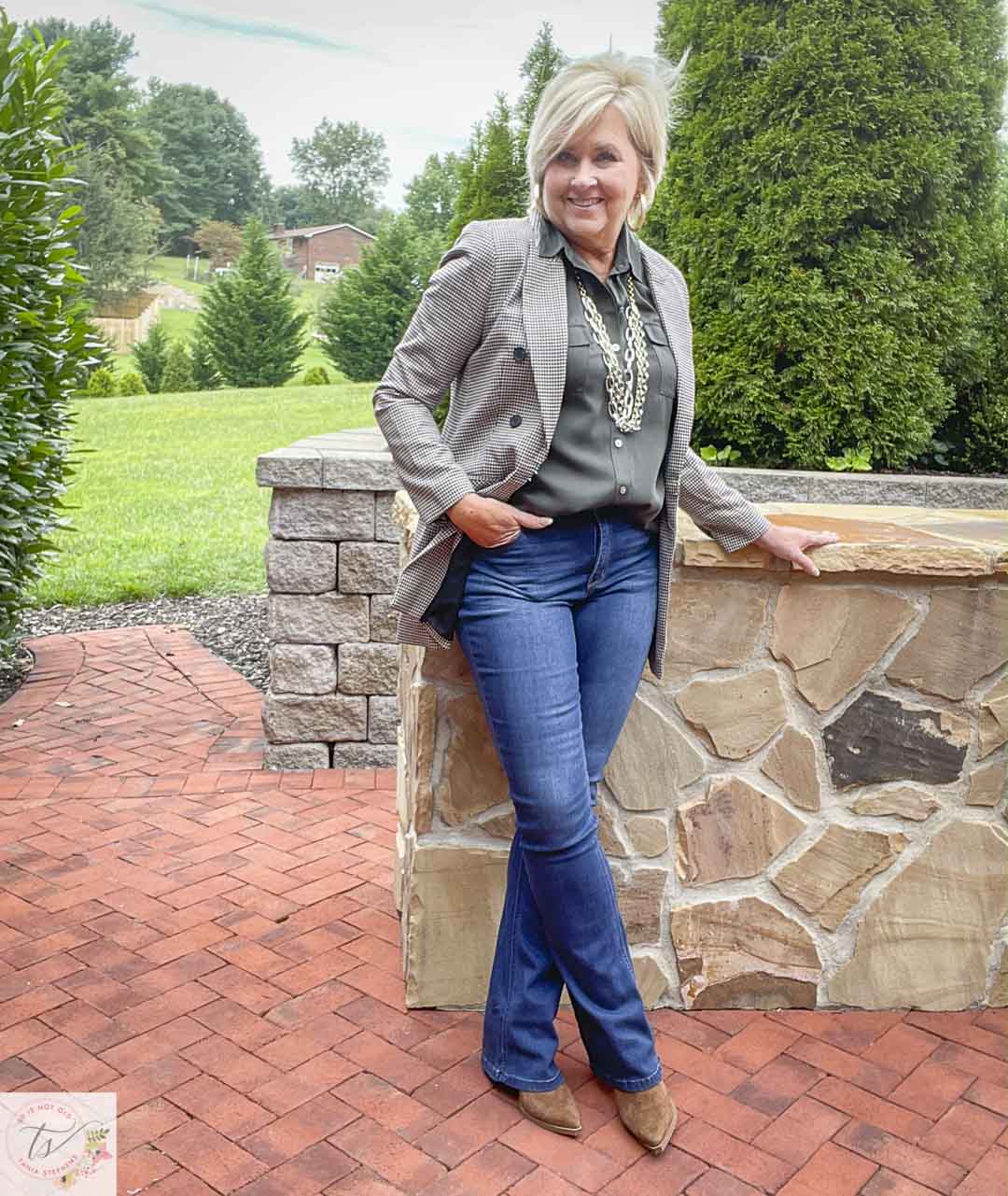 Over 40 Fashion Blogger, Tania Stephens, is wearing a plaid blazer with an olive button-up shirt, bootcut jeans, and suede ankle boots
