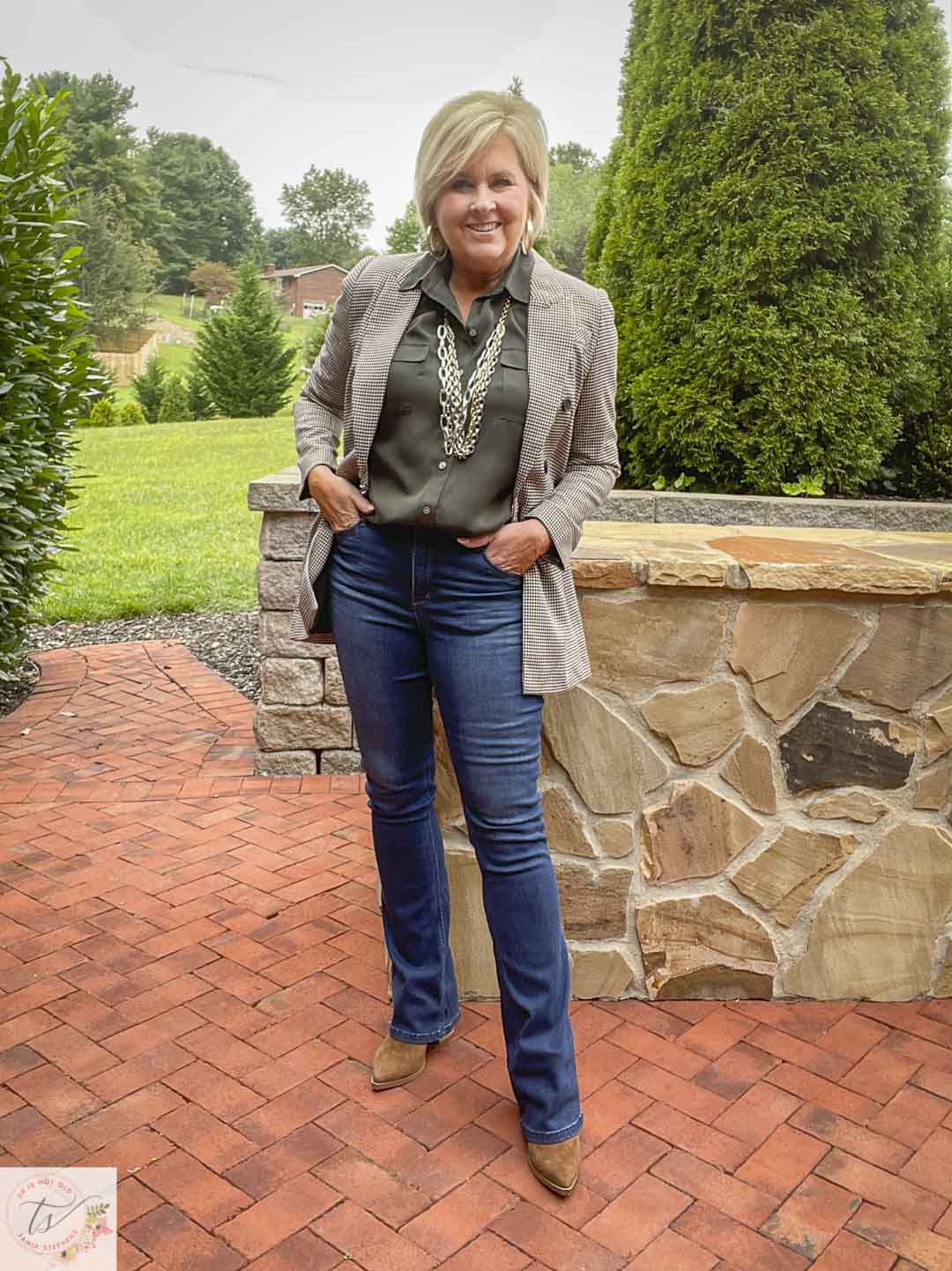 Over 40 Fashion Blogger, Tania Stephens, is wearing a plaid blazer with an olive button-up shirt, slim bootcut jeans, and suede ankle boots