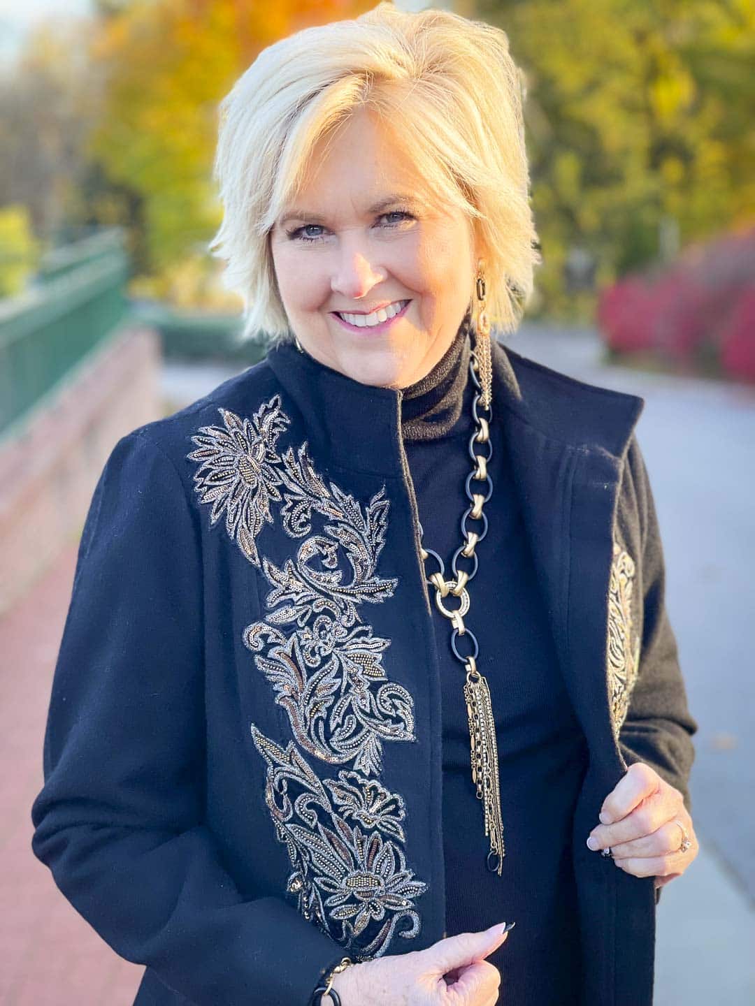 Over 40 Fashion Blogger, Tania Stephens is wearing a black and gold embellished jacket and black and gold jewelry