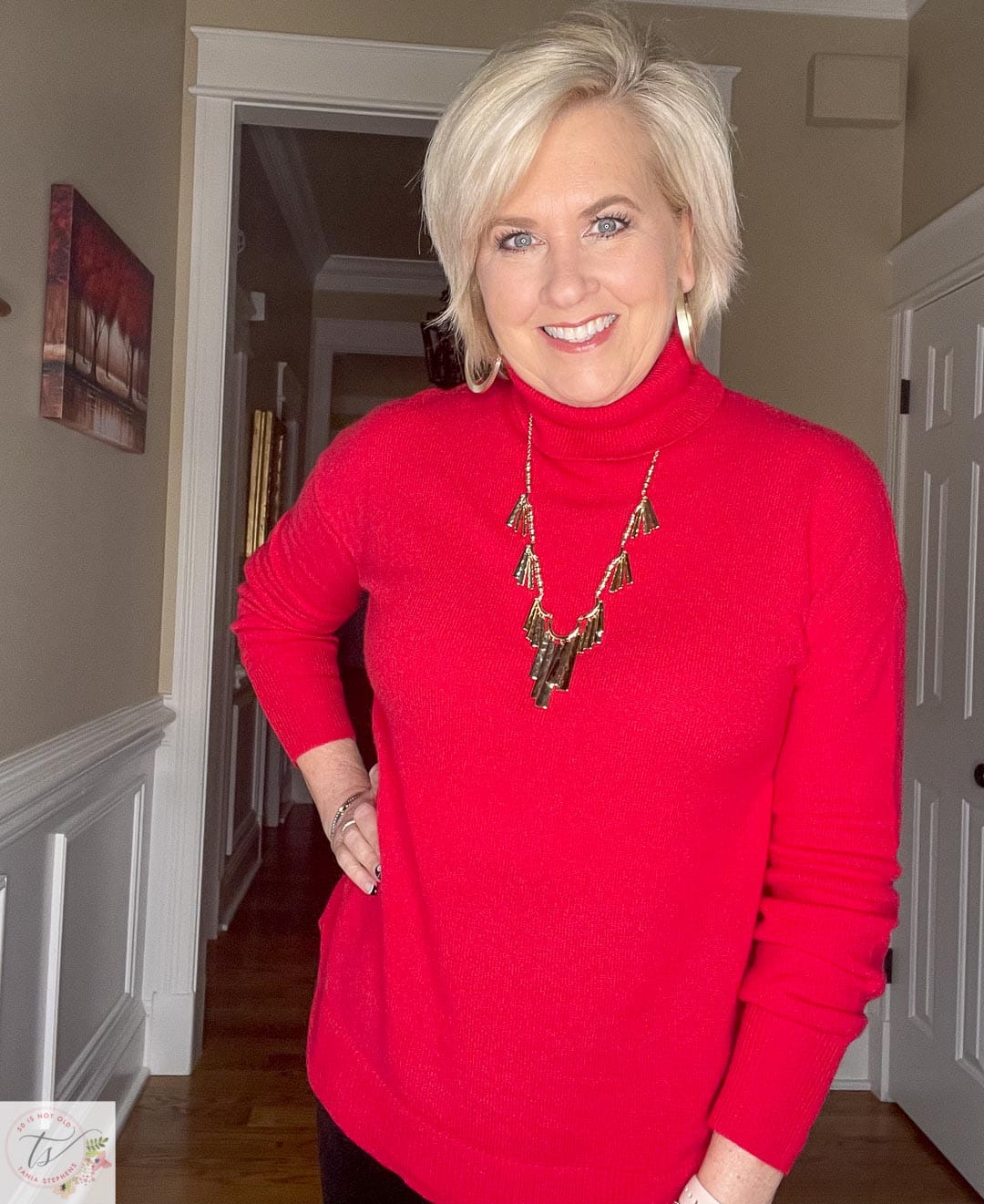 Over 40 Fashion Blogger, Tania Stephens, is celebrating the holidays at home in a red cashmere turtleneck sweater with gold jewelry by Kendra Scott