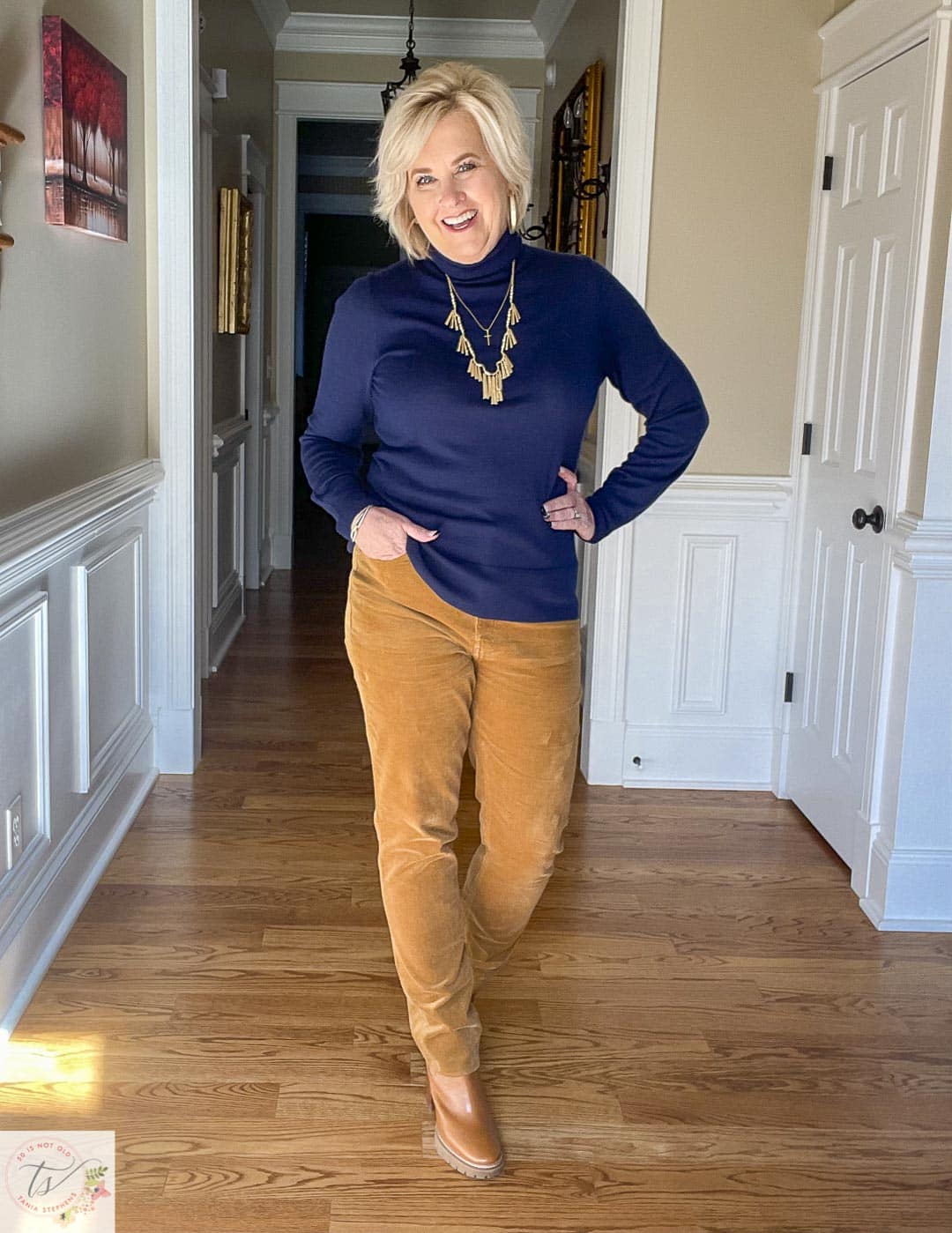 Over 40 Fashion Blogger, Tania Stephens is wearing a navy turtleneck with caramel corduroy pants and gold jewelry from Kendra Scott