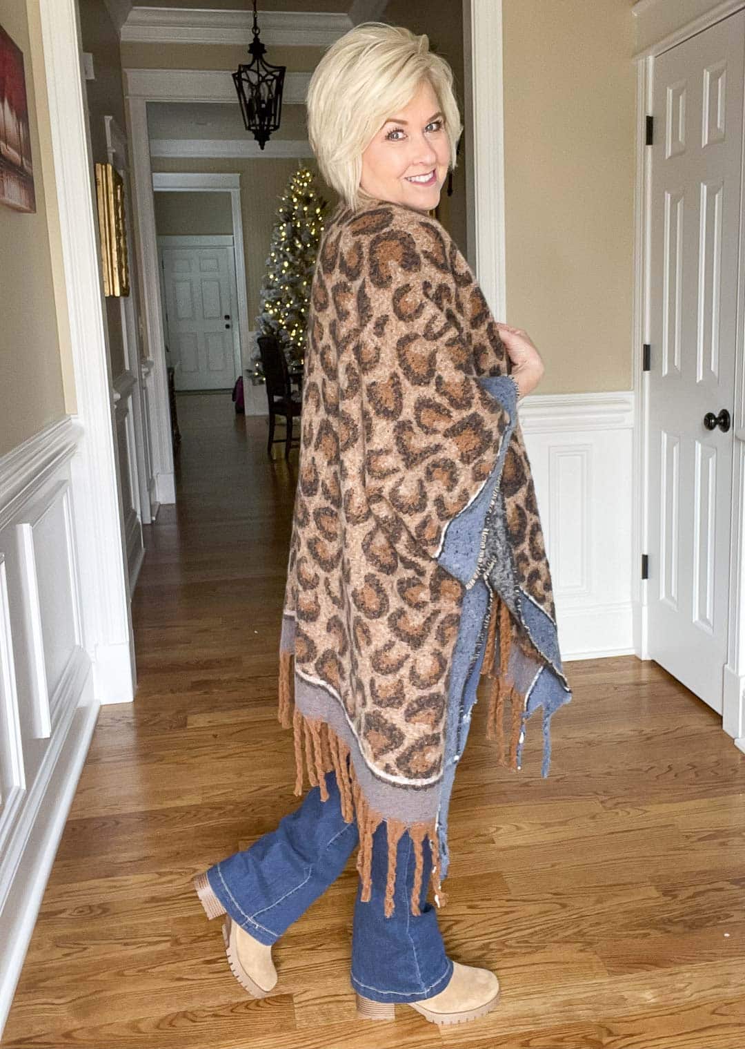 Over 40 Fashion Blogger, Tania Stephens is showing the back of a leopard print blanket wrap, distressed jeans, and a black tee