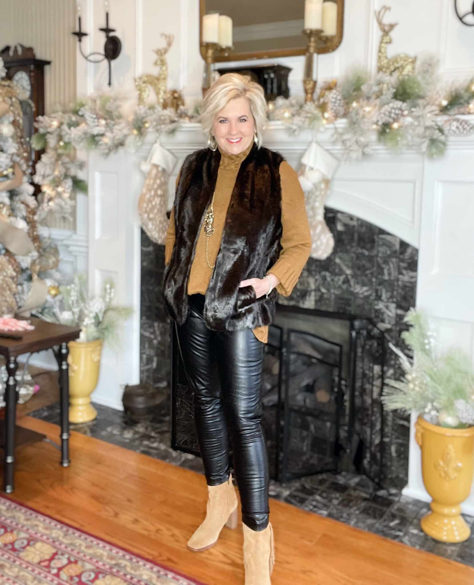 Over 40 Fashion Blogger, Tania Stephens is wearing a pair of faux leather leggings, a camel sweater, a faux fur vest, and ankle boots