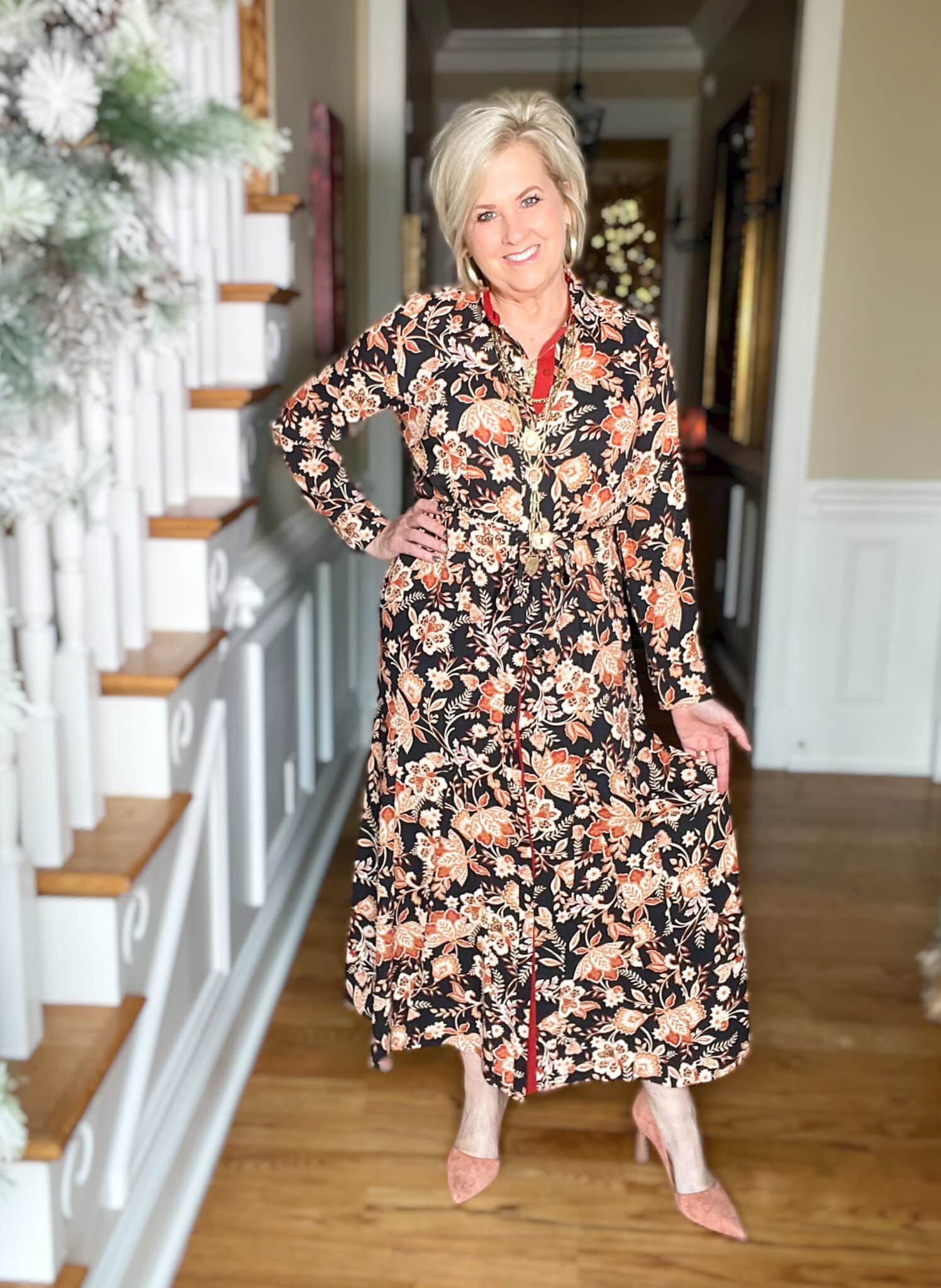 Over 40 Fashion Blogger, Tania Stephens is wearing a floral dress, gold jewelry, and clay colored heels