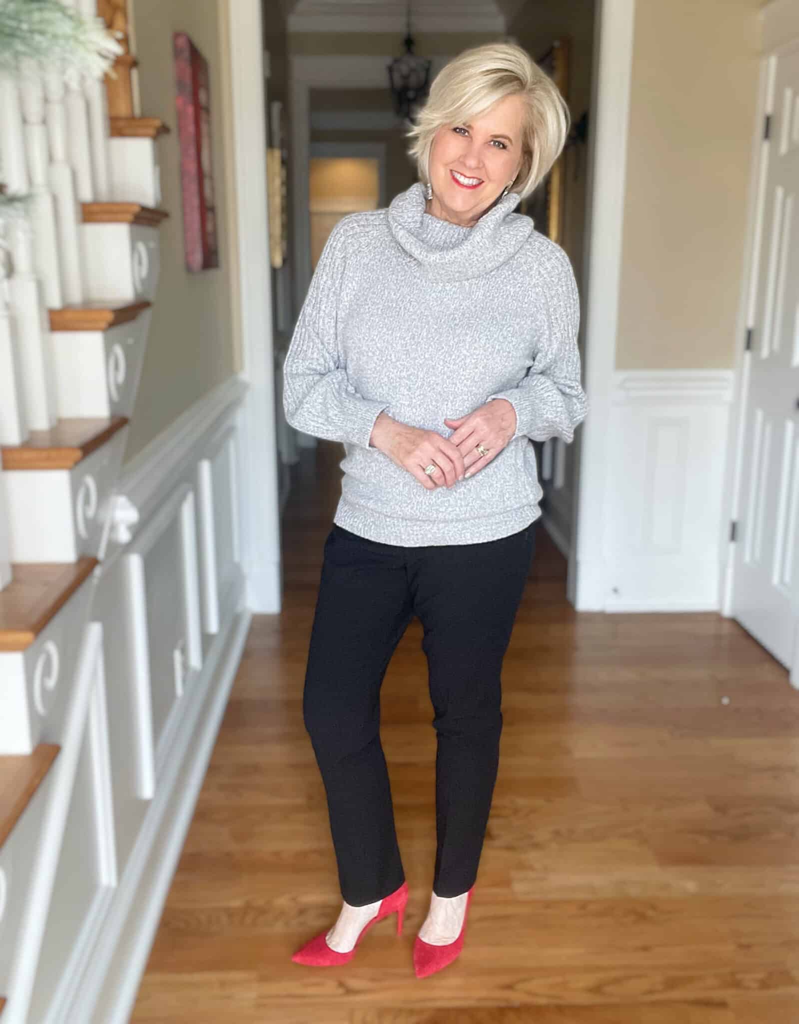 Over 40 Fashion Blogger, Tania Stephens is wearing a gray cowl neck sweater, black ankle pants, and red heels for New Year's Eve 