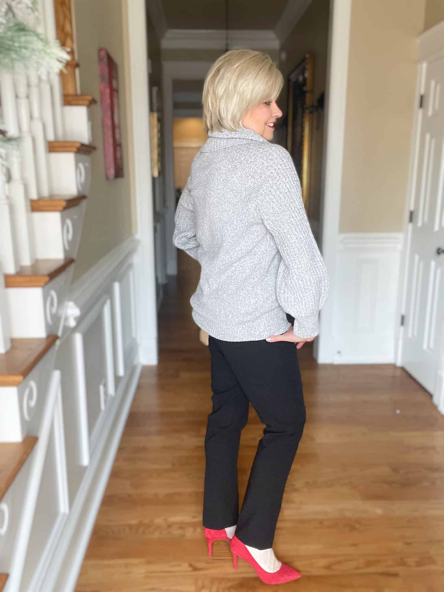 Over 40 Fashion Blogger, Tania Stephens is showing the back of a gray cowl neck sweater with black ankle pants for New Year's Eve