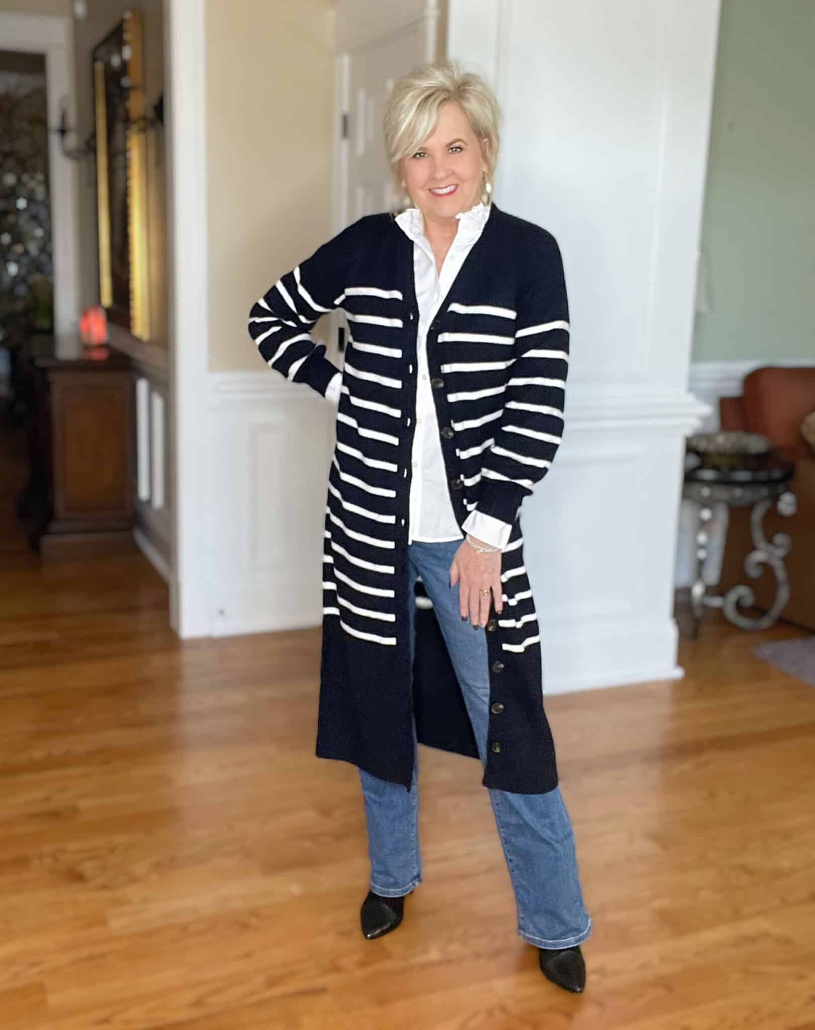 Over 40 Fashion Blogger, Tania Stephens is wearing a long navy and white cardigan with a white button up shirt, jeans, and boots