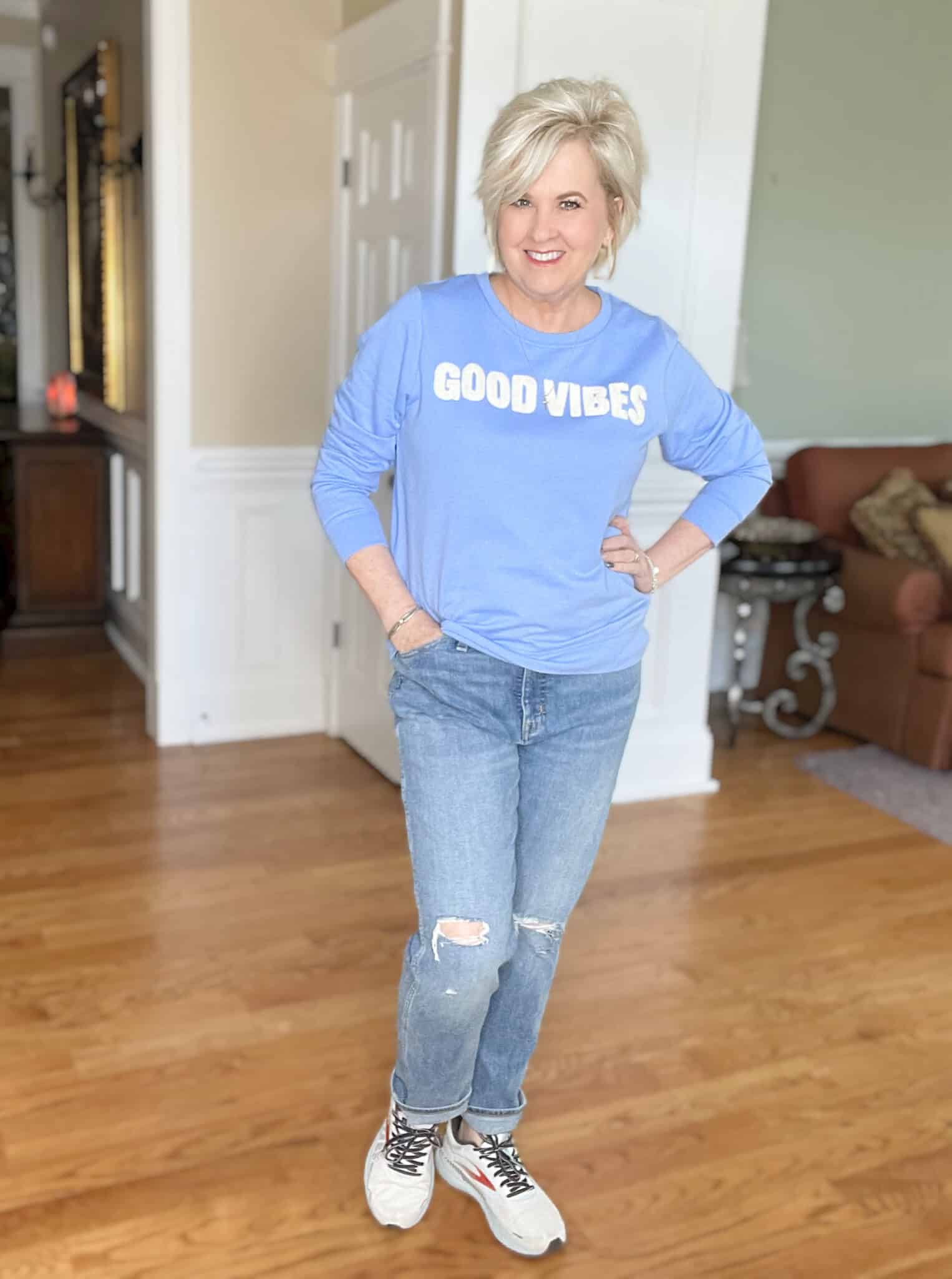 Over 40 Fashion Blogger, Tania Stephens is cozy in this blue Good Vibes sweatshirt and distressed jeans from Loft