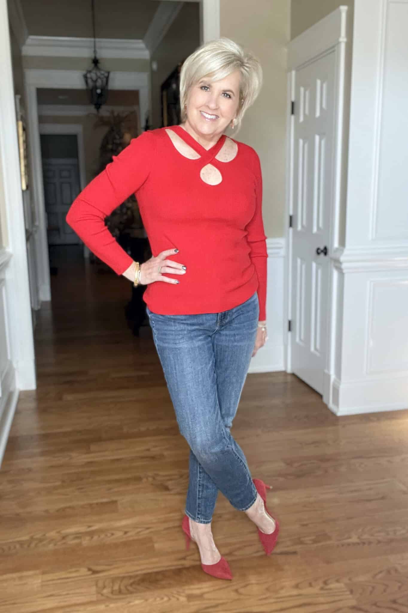 Over 40 Fashion Blogger, Tania Stephens is wearing a red sweater, jeans, and red heels