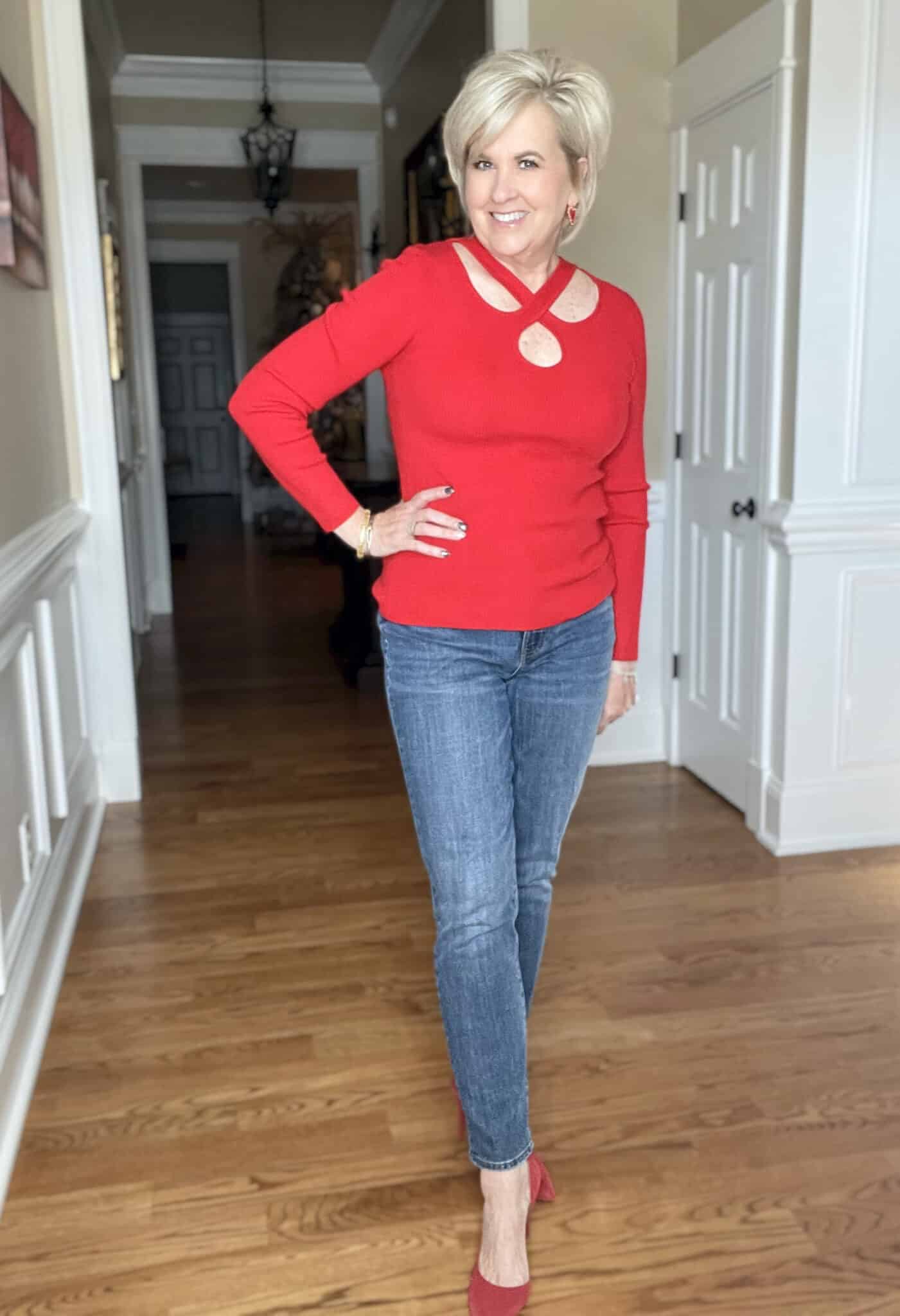 Over 40 Fashion Blogger, Tania Stephens is wearing a bright red sweater, jeans, and red heels
