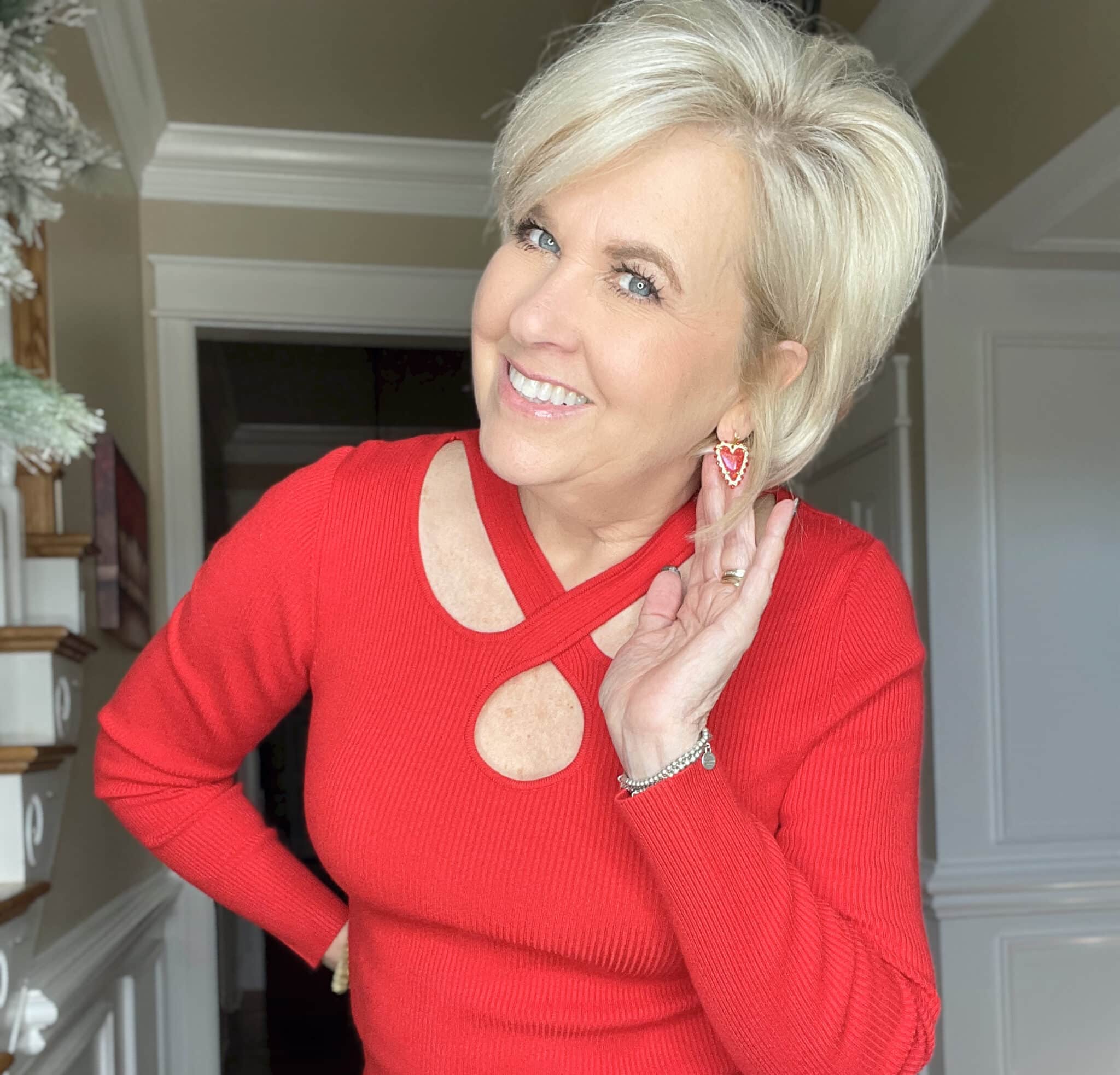 Over 40 Fashion Blogger, Tania Stephens is wearing a bright red sweater with heart earrings