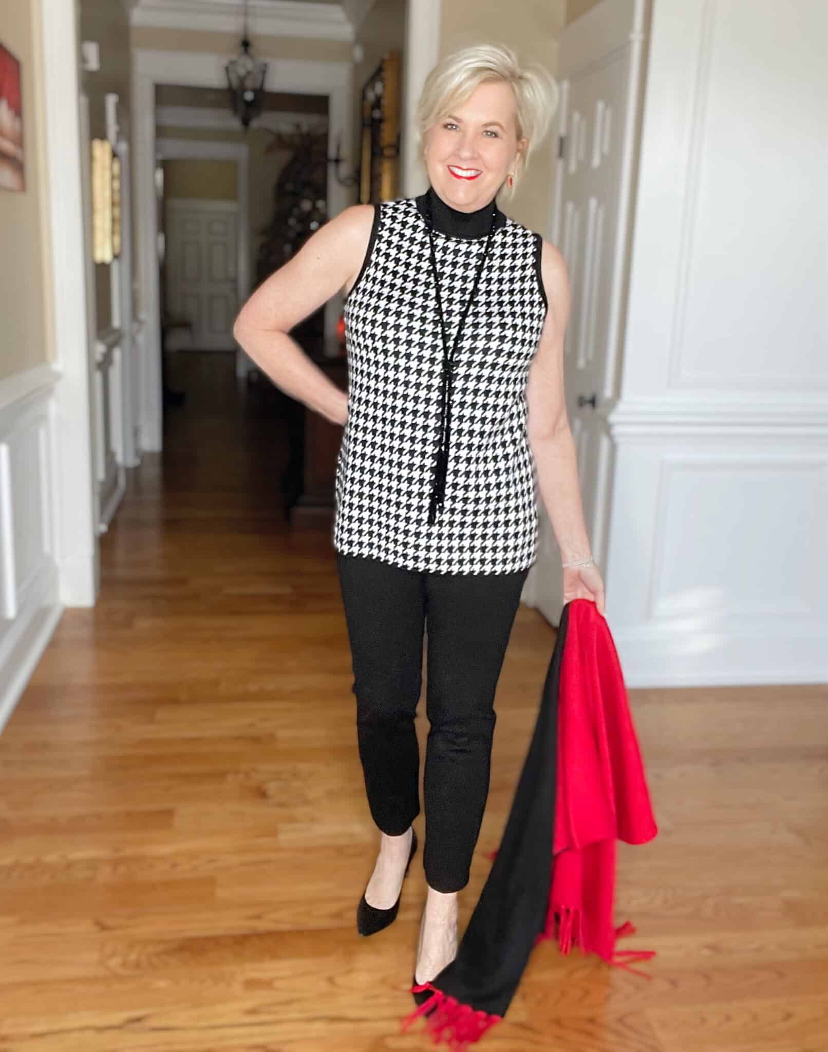 Over 40 Fashion Blogger, Tania Stephens is dressed in a herringbone print sweater, black pants, and black pumps