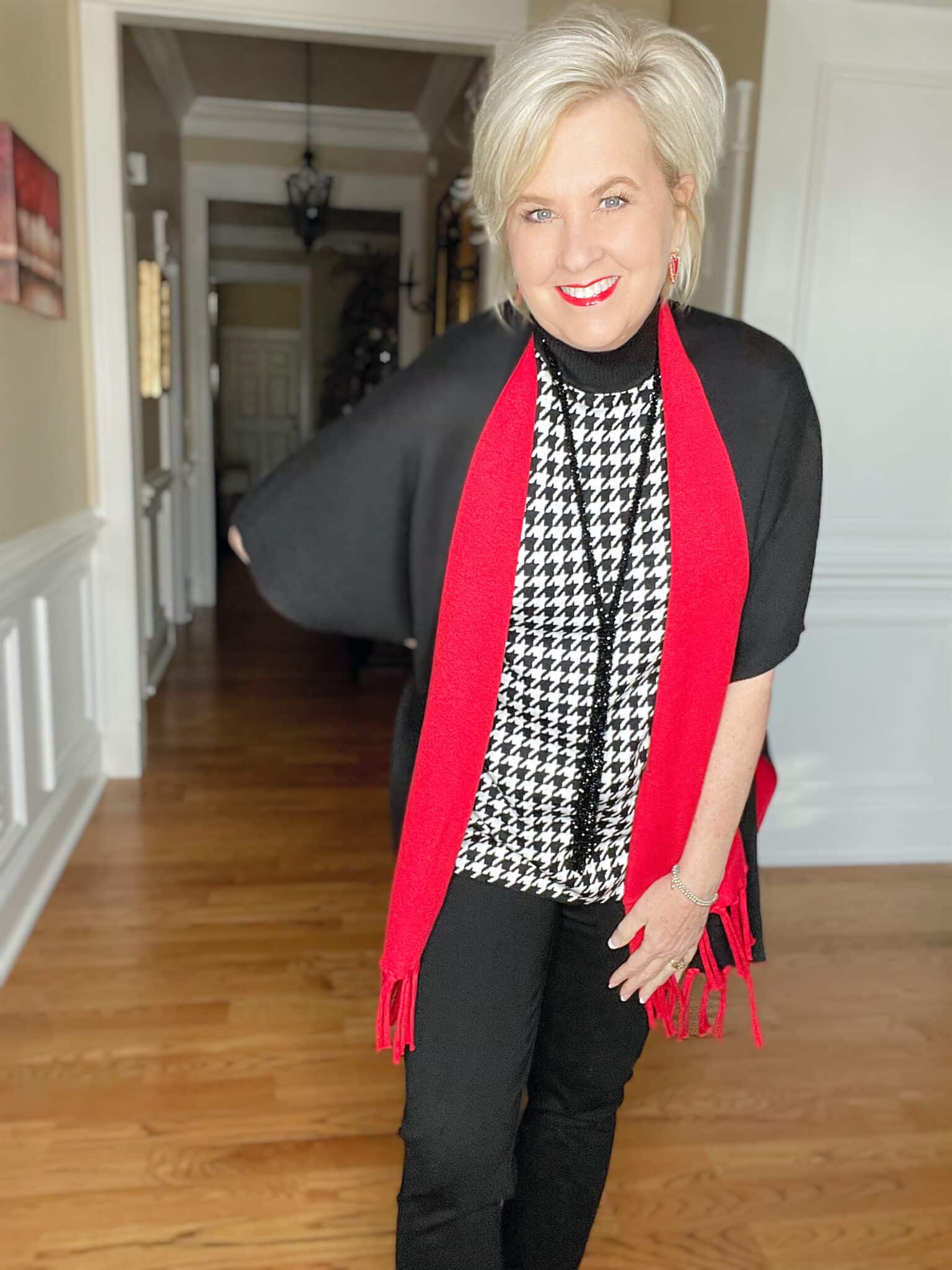 Over 40 Fashion Blogger, Tania Stephens is dressed in a herringbone print sweater, and a black/red reversible ruana