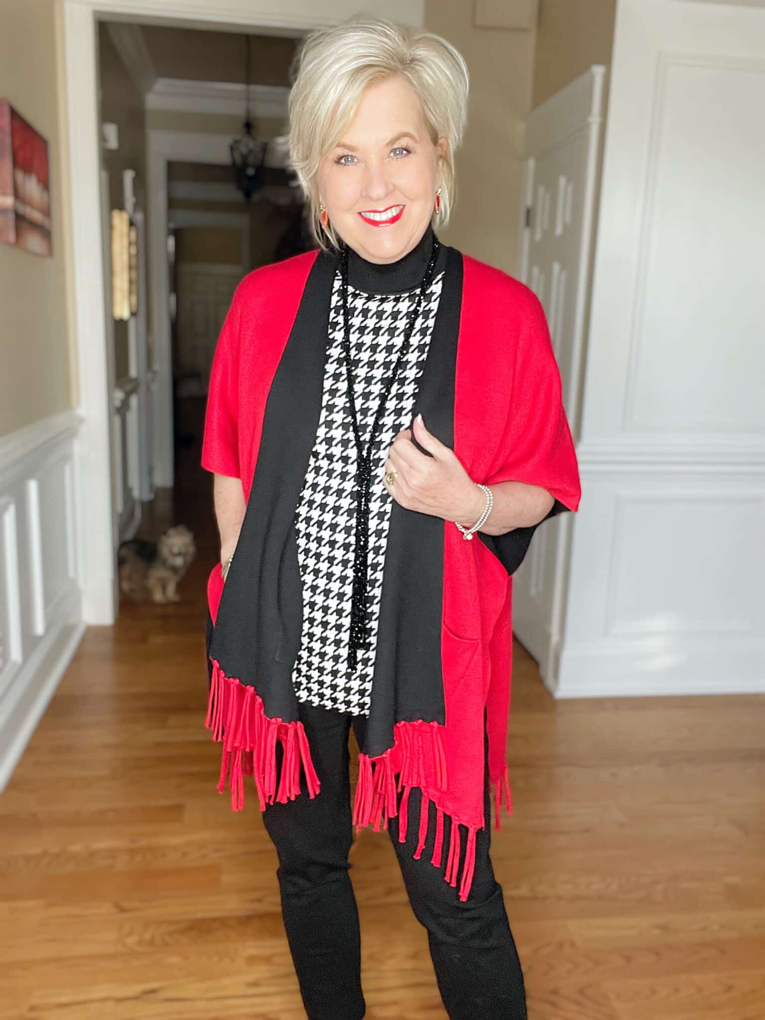 Over 40 Fashion Blogger, Tania Stephens is dressed in a herringbone print sweater, and a red/black reversible ruana