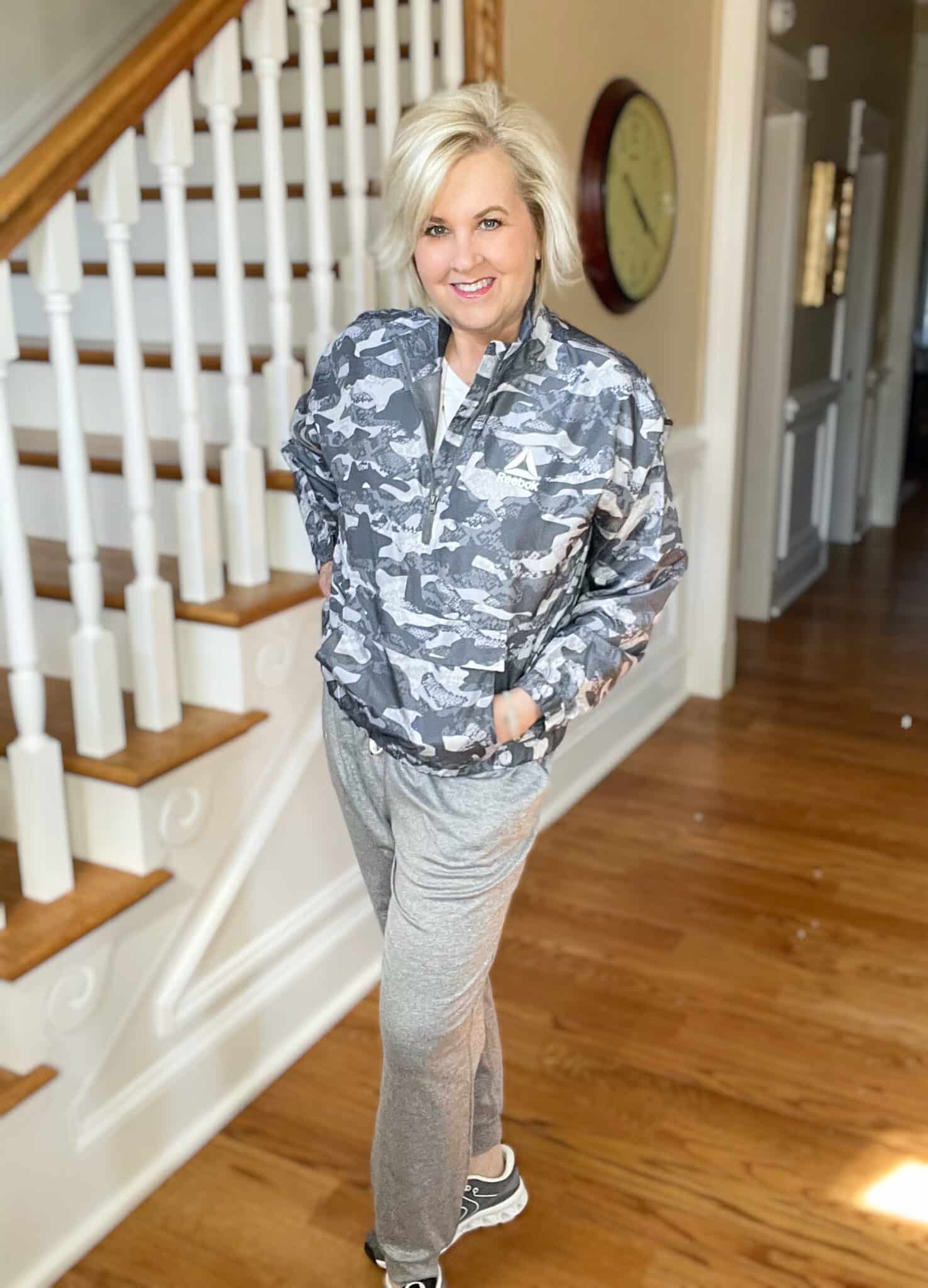 Over 40 Fashion Blogger, Tania Stephens is wearing a gray camo windbreaker, a white v-neck t-shirt, gray joggers, and gray sneakers