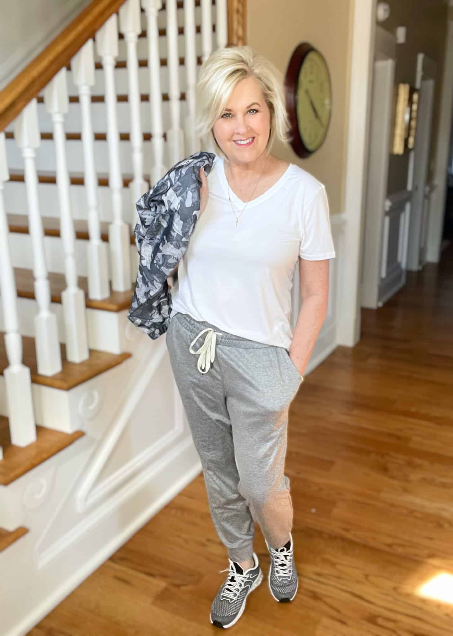 Over 40 Fashion Blogger, Tania Stephens is wearing a white v-neck t-shirt, a camo windbreaker, gray joggers, and gray sneakers