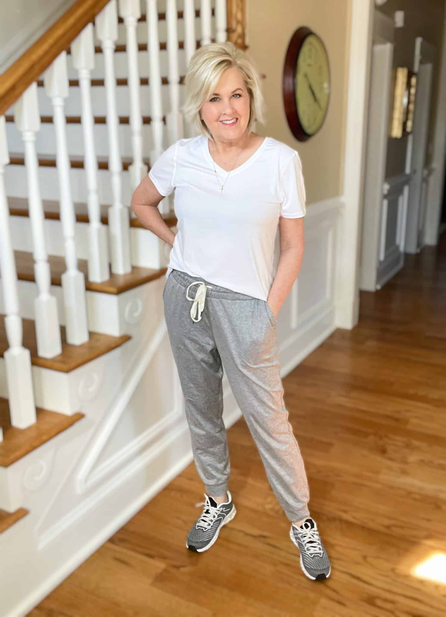 Over 40 Fashion Blogger, Tania Stephens is wearing a white v-neck t-shirt with gray joggers, and gray sneakers