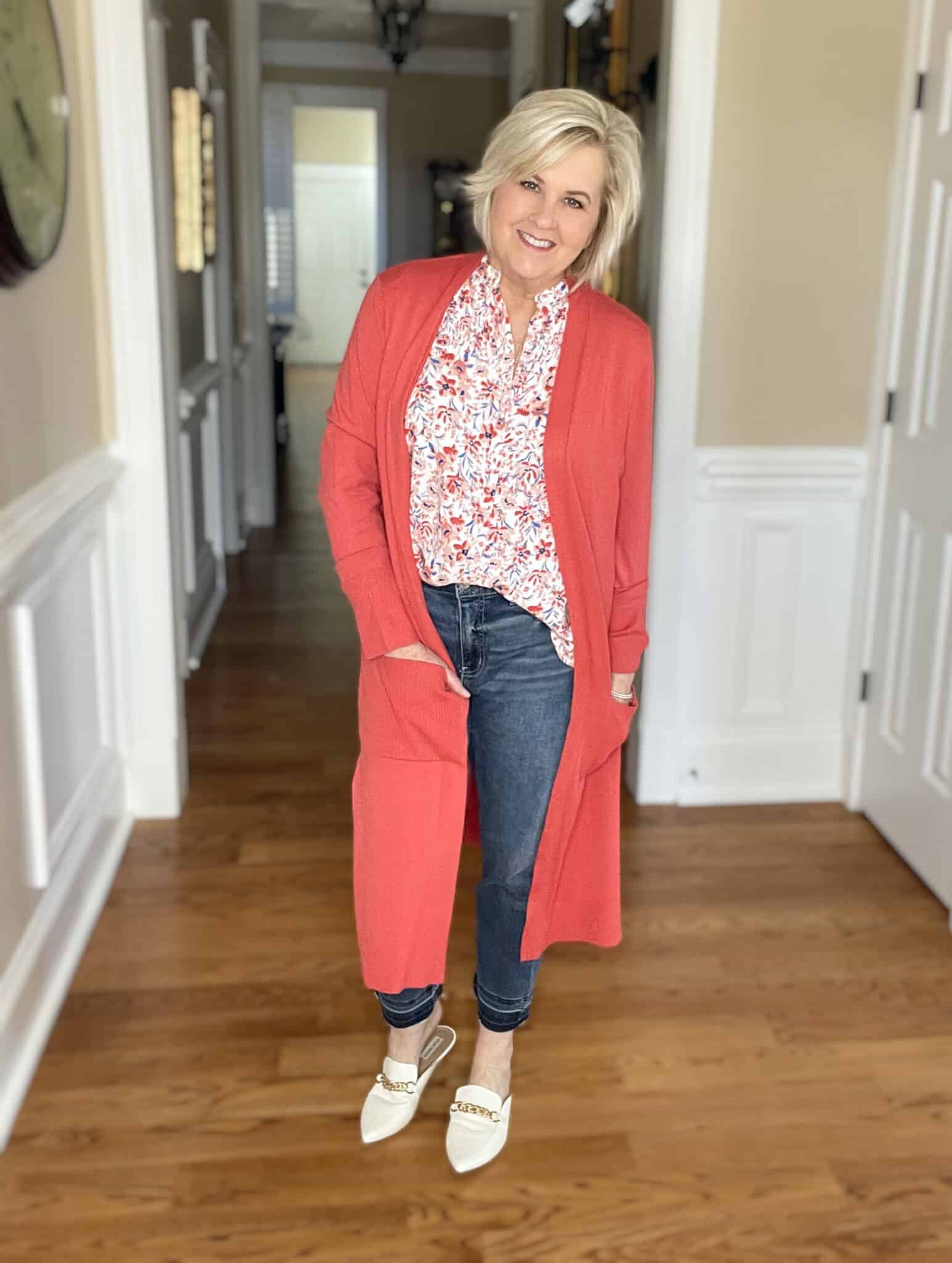 Over 40 Fashion Blogger, Tania Stephens is wearing a floral top with jeans and a long orange duster