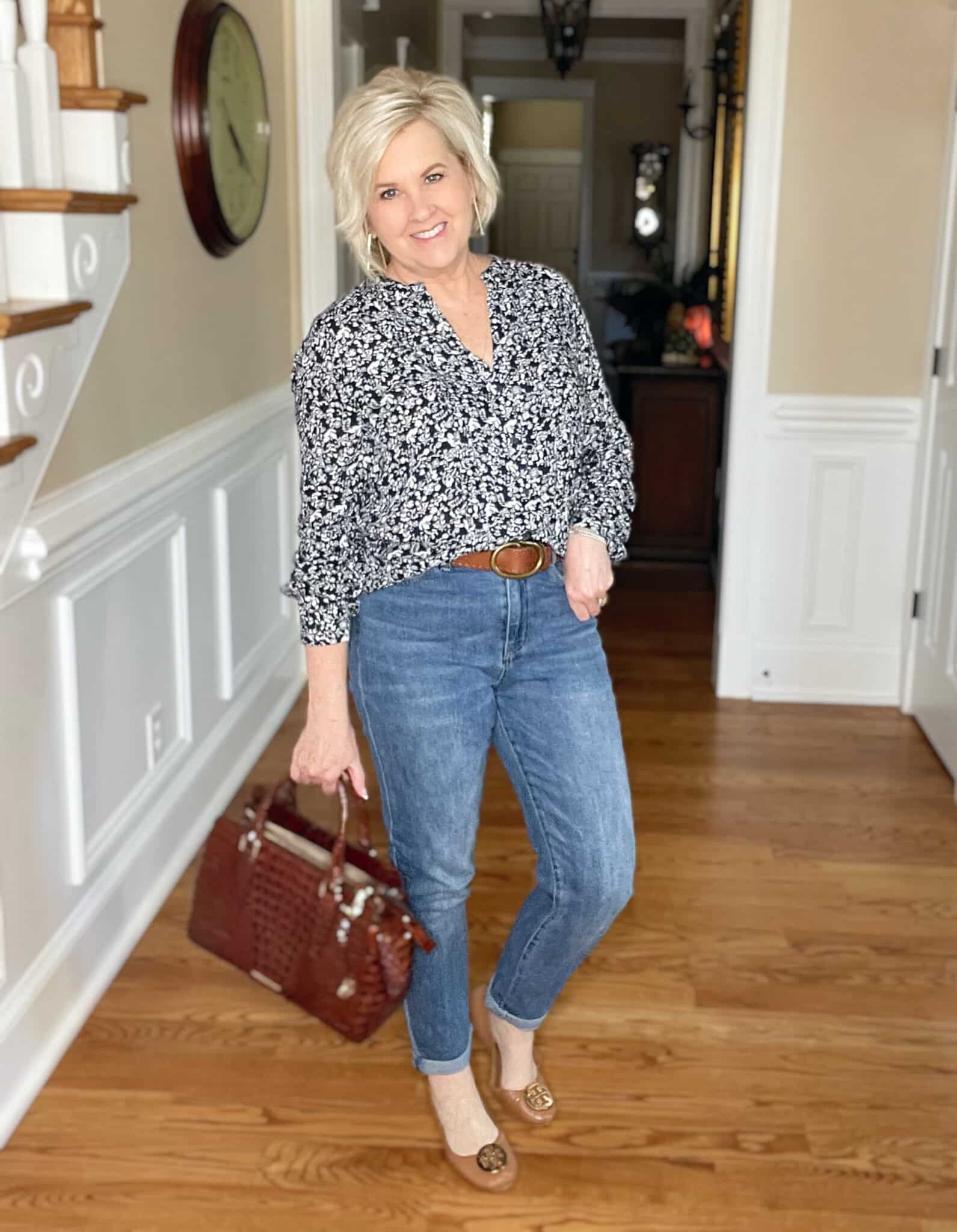 Over 40 Fashion Blogger, Tania Stephens is wearing a navy and white floral top, jeans, and carrying a Brahmin pecan handbag