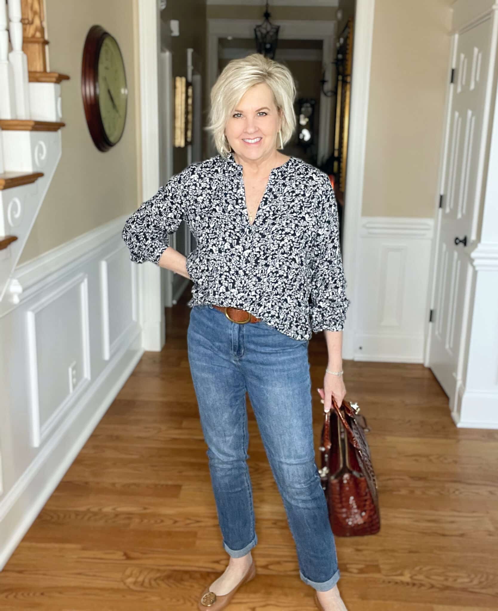 Over 40 Fashion Blogger, Tania Stephens is wearing a navy and white floral top, jeans, flats, and carrying a Brahmin handbag