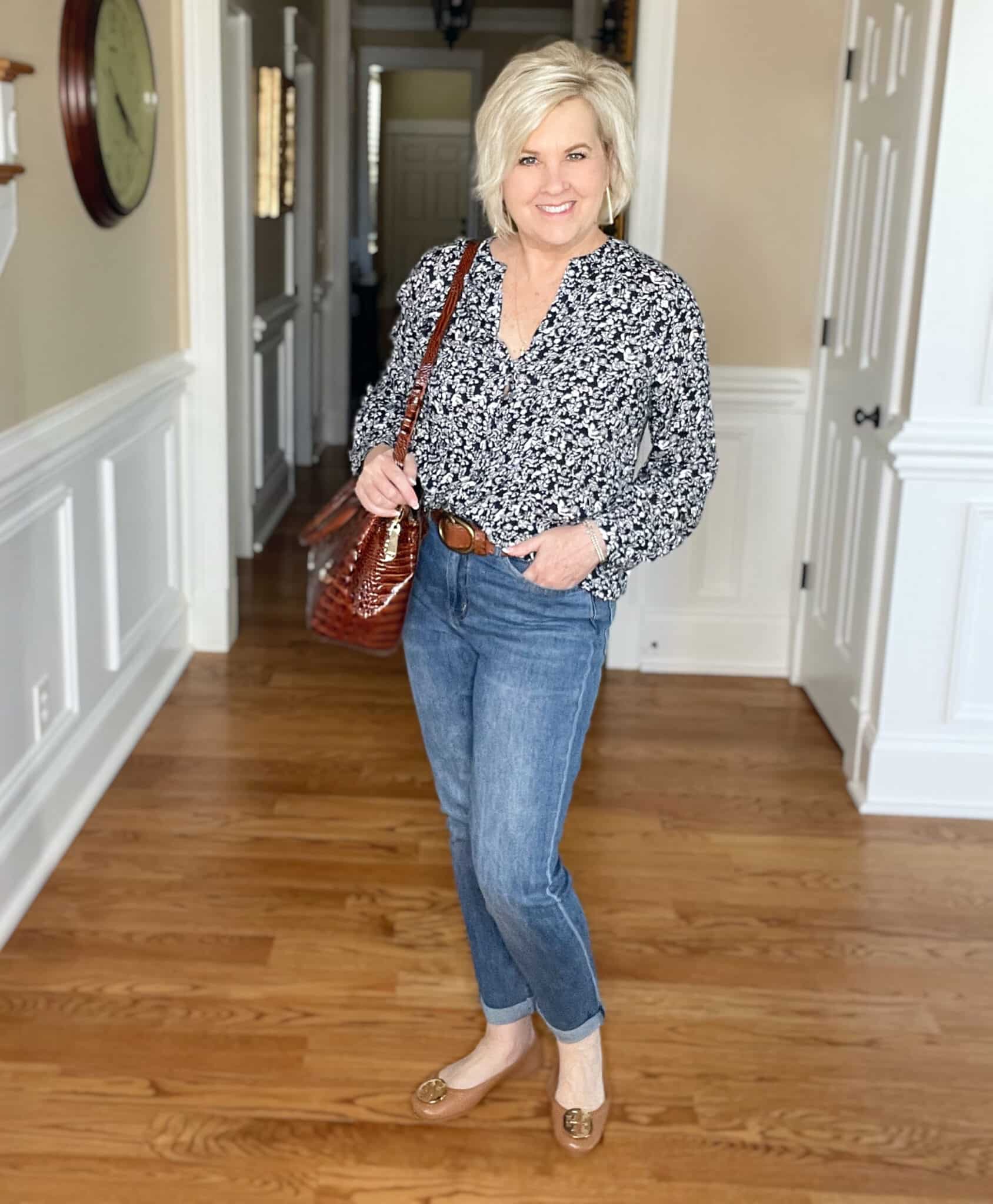 Over 40 Fashion Blogger, Tania Stephens is wearing a navy and white floral top, jeans, and carrying a Brahmin brown handbag