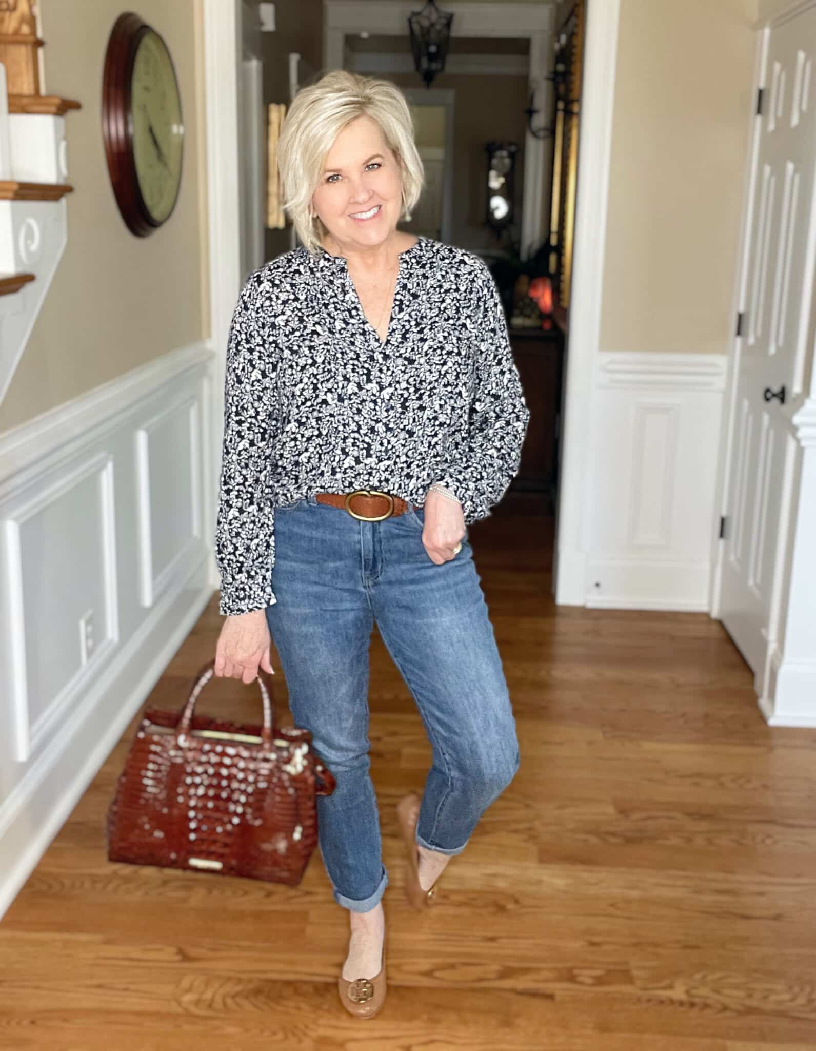 Over 40 Fashion Blogger, Tania Stephens is wearing a navy and white floral top, jeans, and carrying a Brahmin handbag