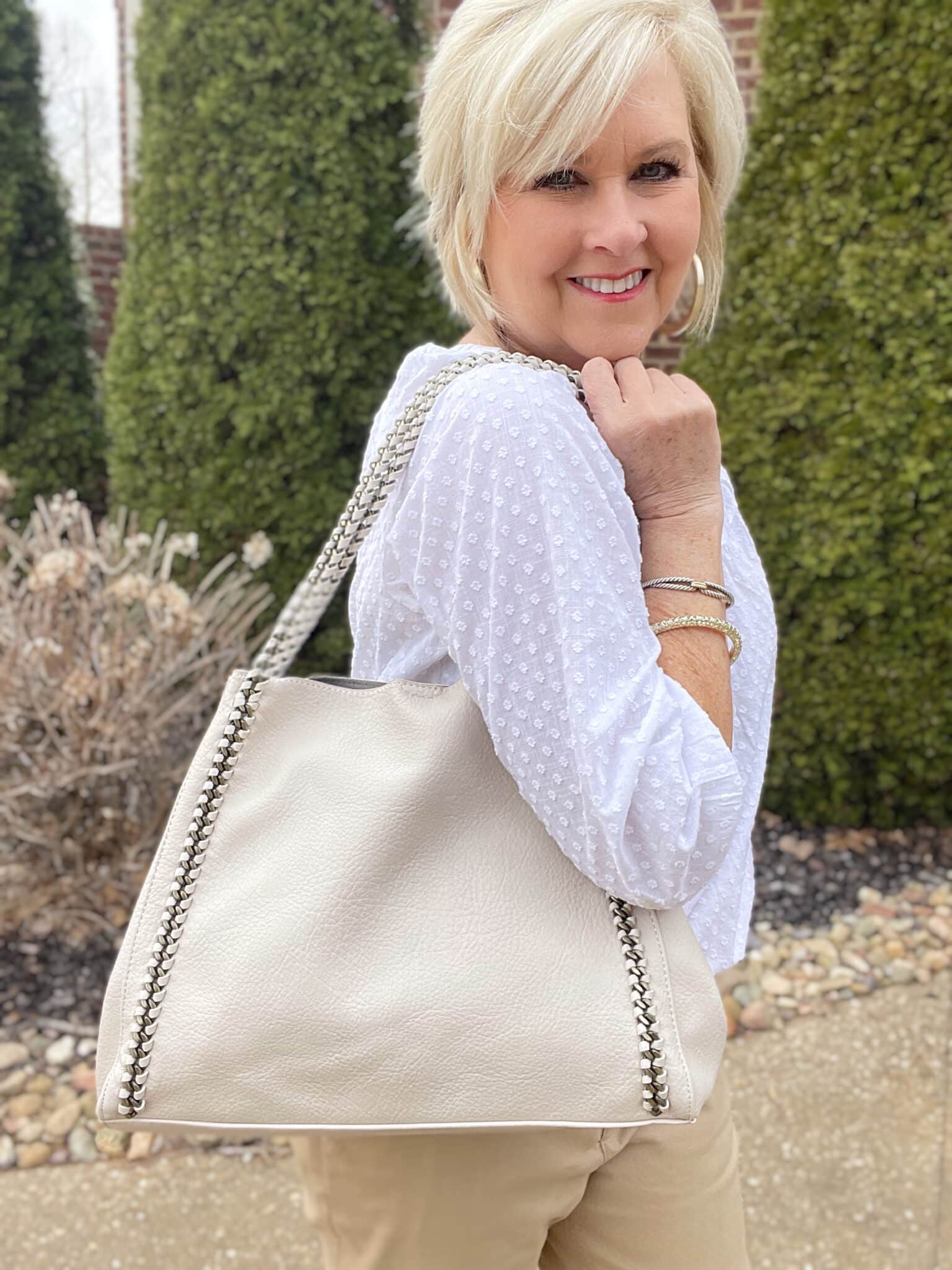 Over 40 Fashion Blogger, Tania Stephens is styling a white henley blouse with an ivory handbag