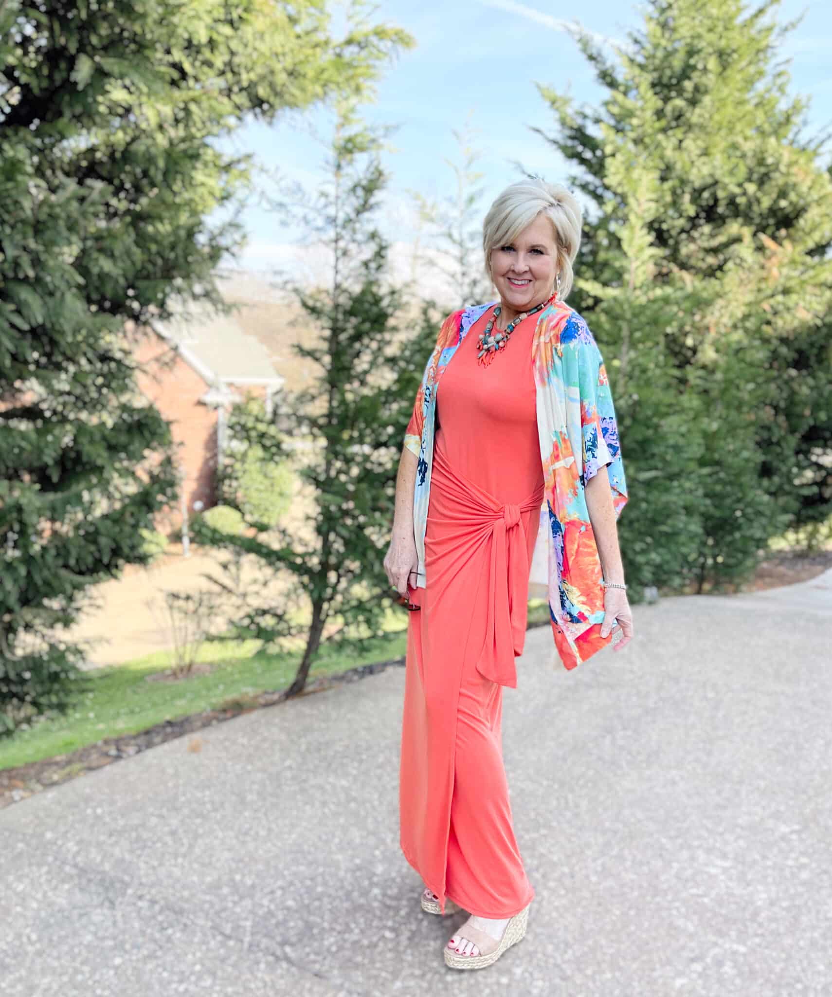 Over 40 Fashion Blogger, Tania Stephens is wearing an orange maxi dress with an agua colored Ruana