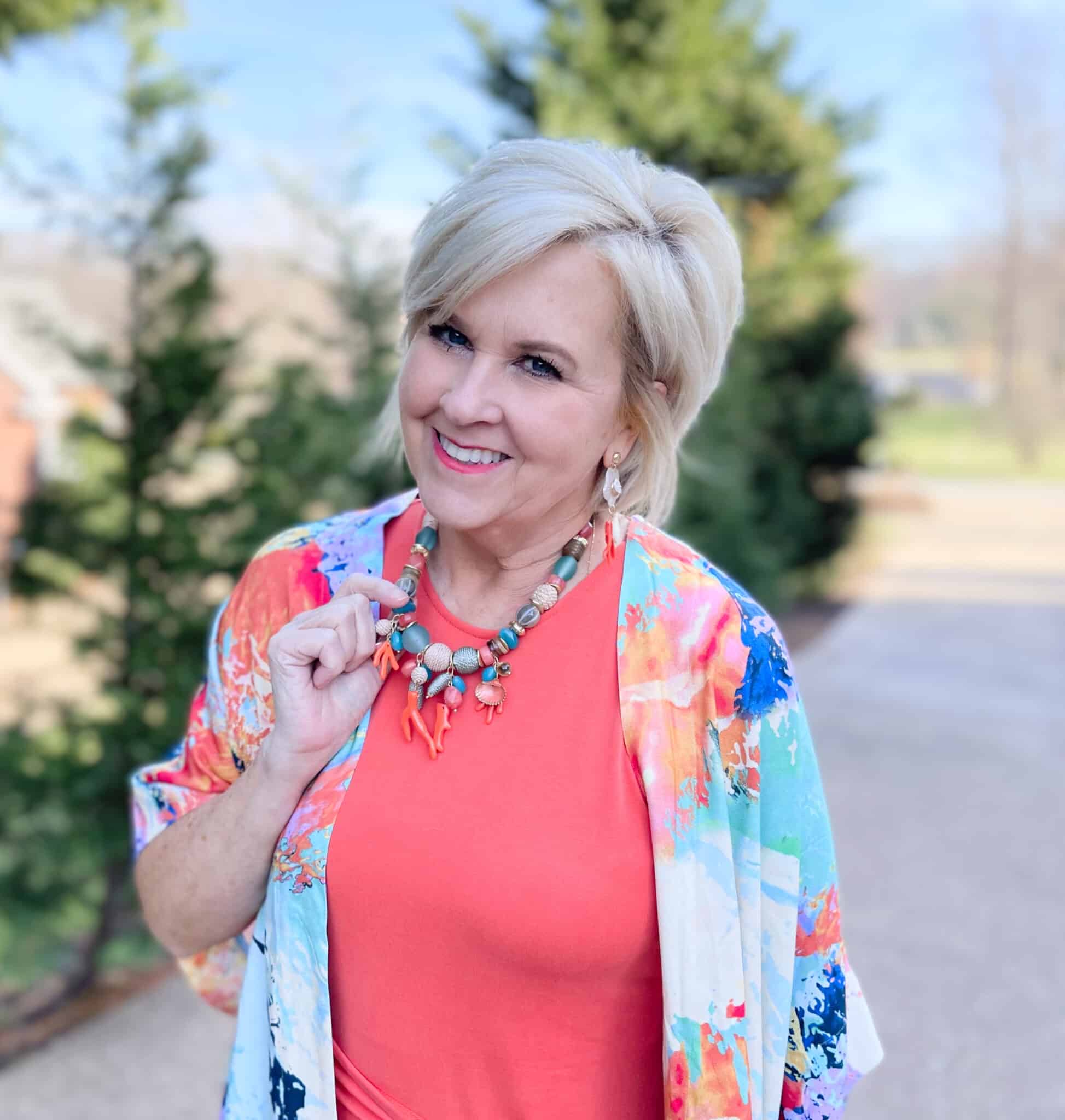 Over 40 Fashion Blogger, Tania Stephens is wearing an orange dress with a colorful necklace