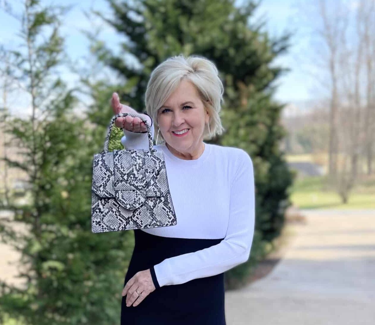Over 40 Fashion Blogger, Tania Stephens is wearing a white and black dress with a small snakeskin bag