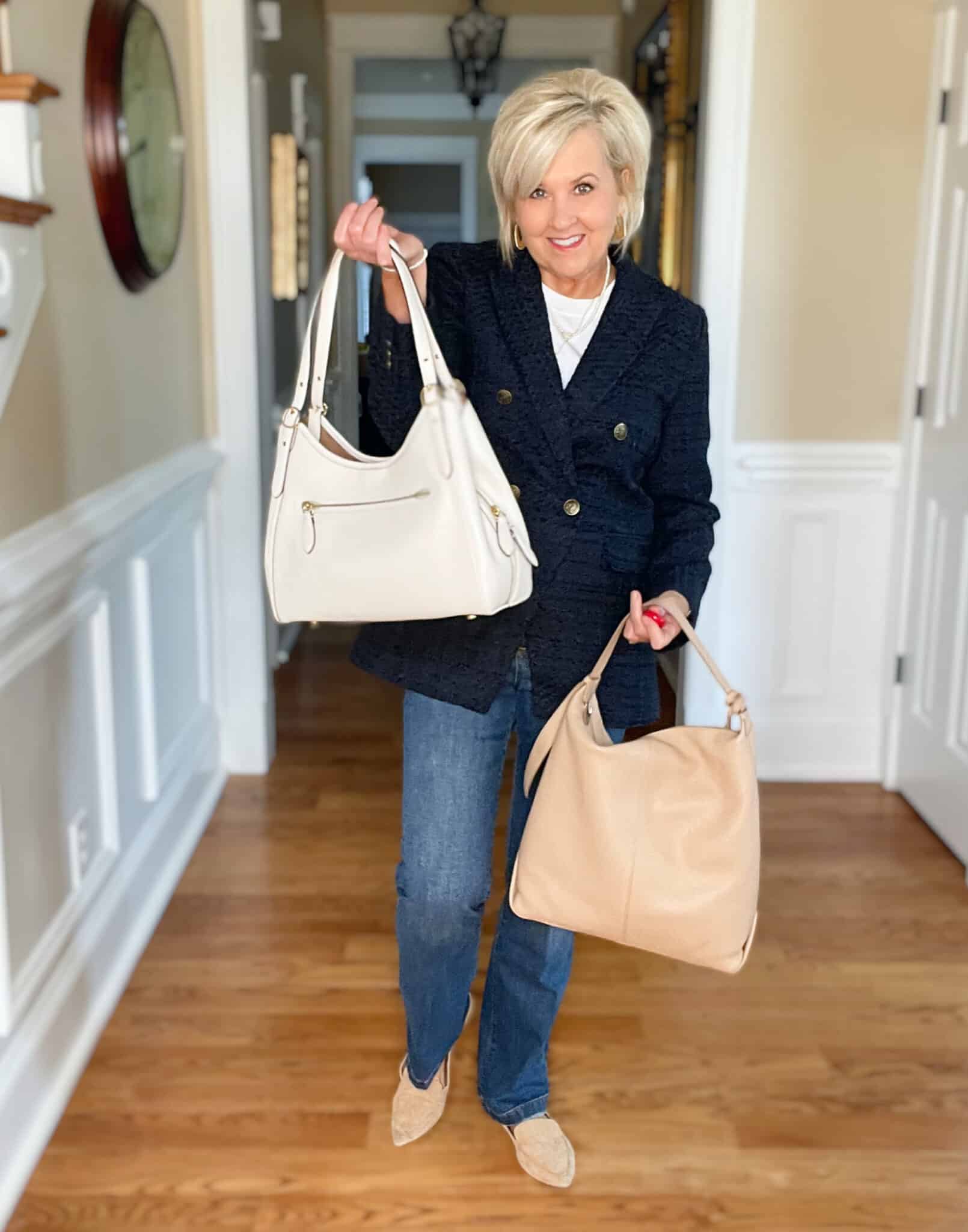 Over 40 Fashion Blogger, Tania Stephens is wearing a white cashmere blend tee, straight cut jeans, a navy double breasted blazer, and carrying a neutral handbags