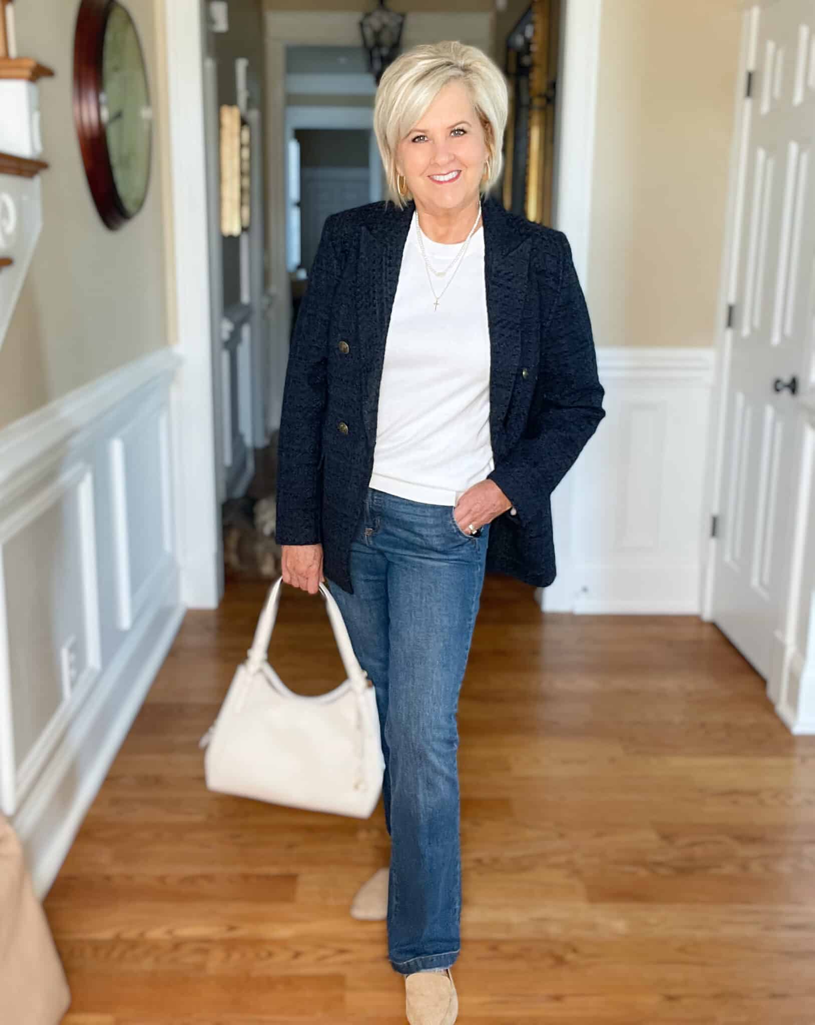 Over 40 Fashion Blogger, Tania Stephens is wearing a white cashmere blend tee, straight cut jeans, a navy double breasted blazer, and carrying a neutral handbag