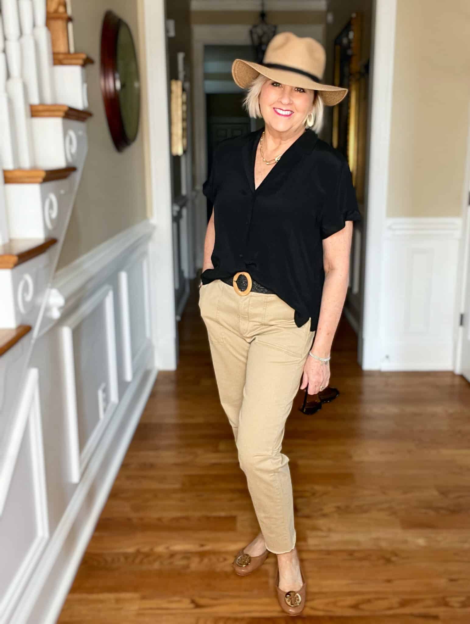 Over 40 Fashion Blogger, Tania Stephens is wearing a black short sleeve shirt with tan pants and a straw fedora