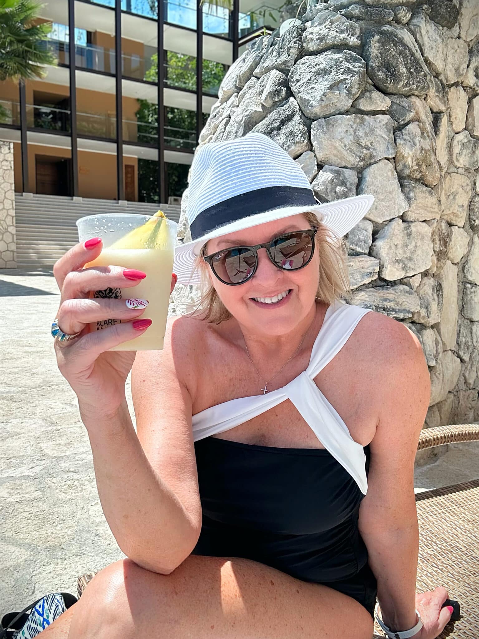Fashion Blogger, Tania Stephens is holding a drink and wearing a black and white tankini.
