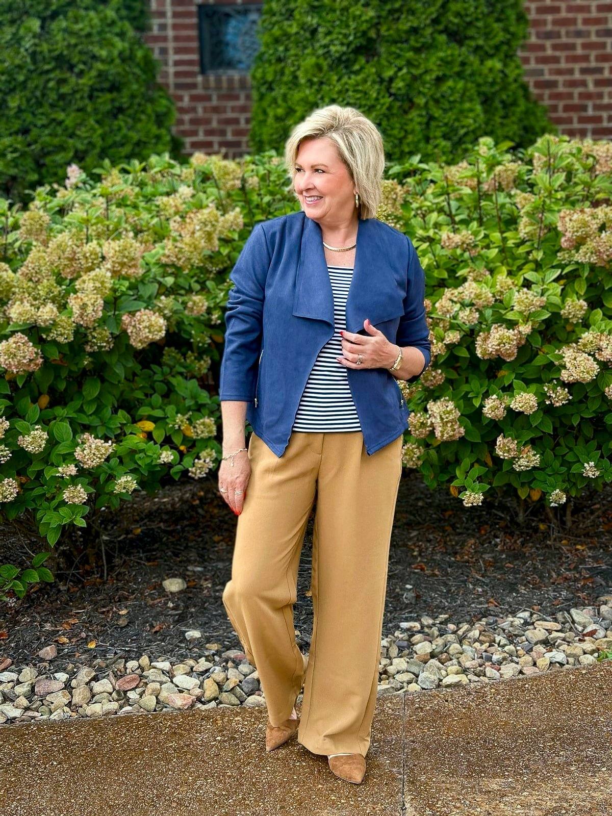 Tania Stephens is wearing a navy jacket, striped top, and camel trousers