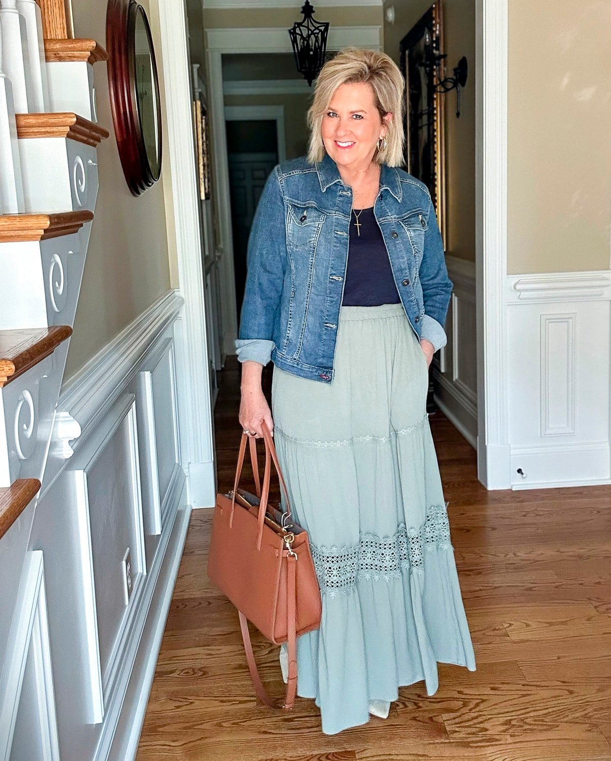 Tania Stephens wearing a sage green lace maxi skirt with a denim jacket and navy tank, styled with neutral flats—an elegant way to wear summer earth tones.