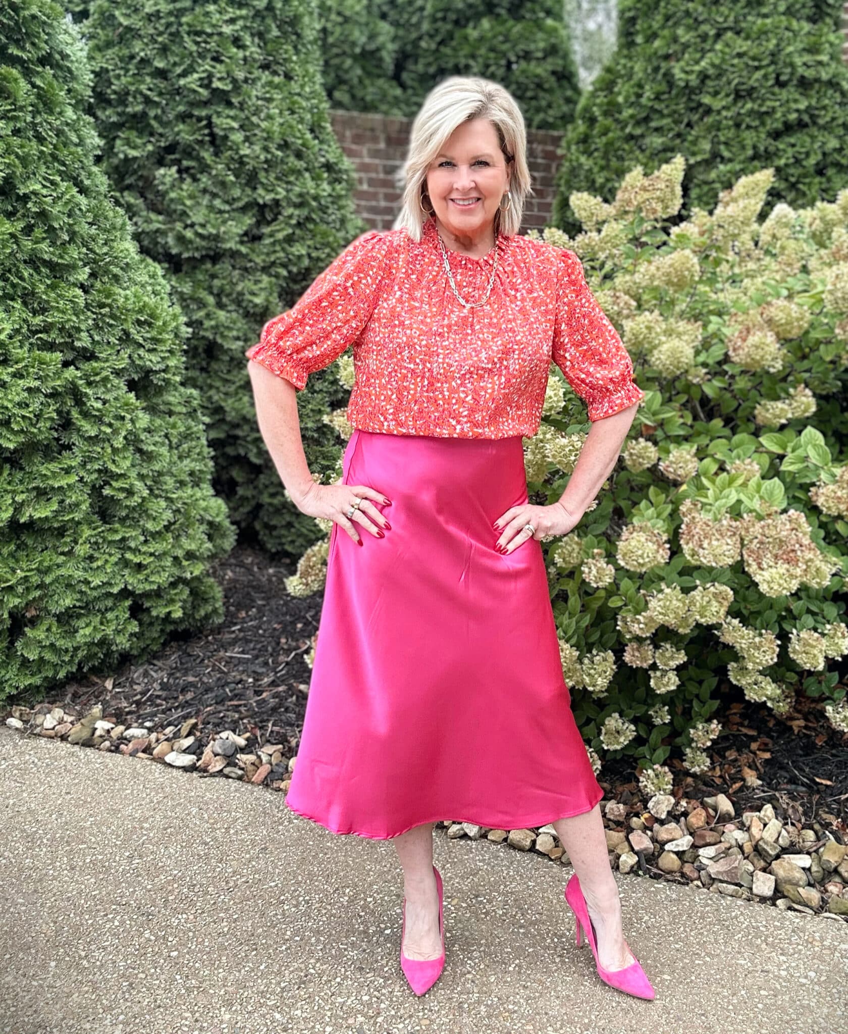 Fashion Blogger Tania Stephens is wearing a red/orange top with a magenta silk skirt