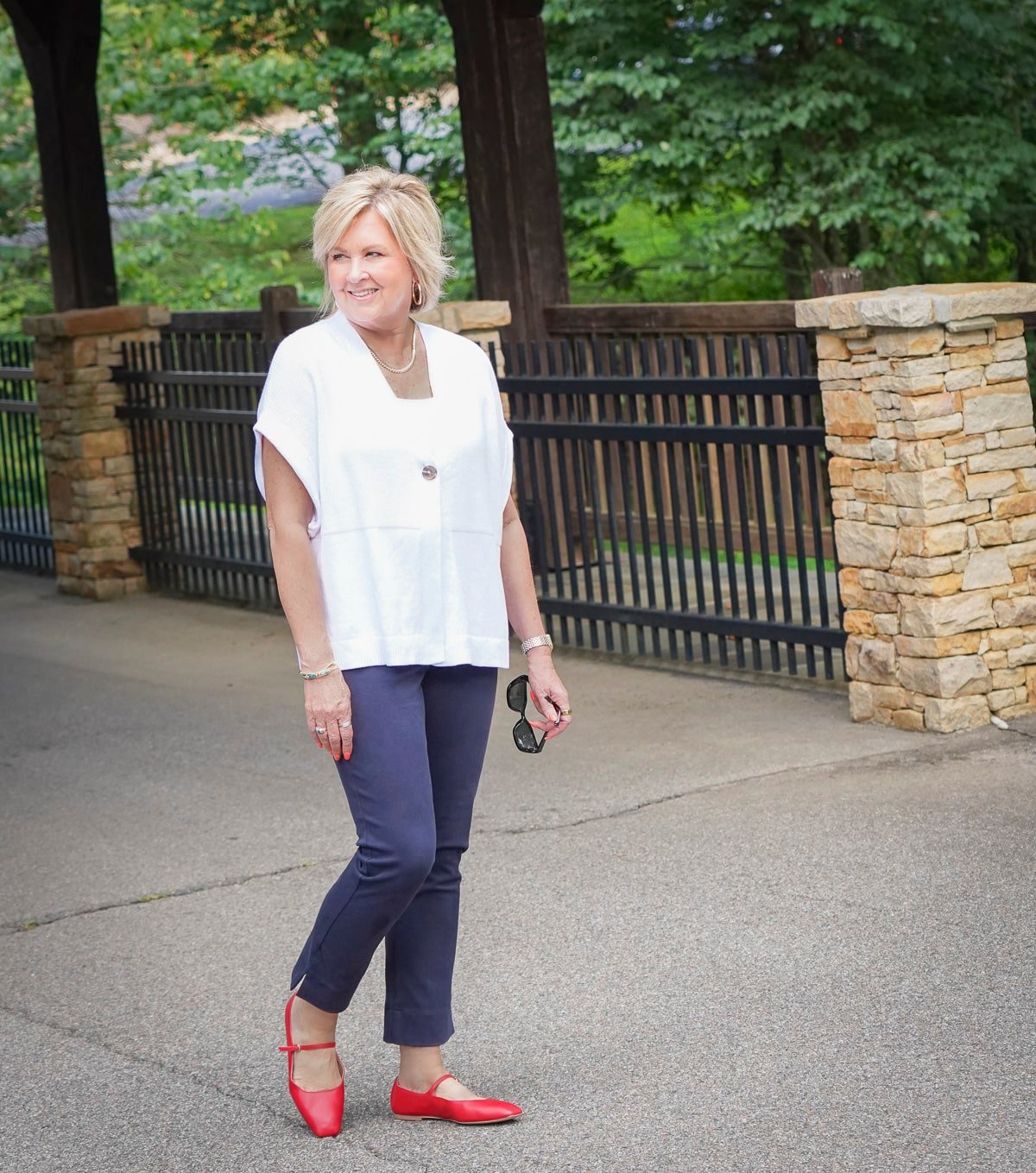 Tania Stephens is wearing a white cardigan and navy pants with fiery red flats
