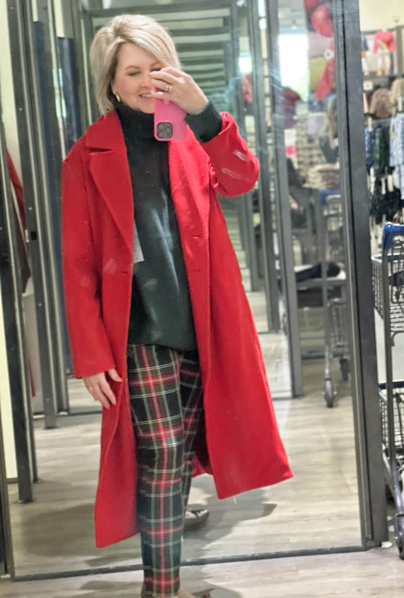 Tania is wearing a red coat, a green sweater, and plaid pants