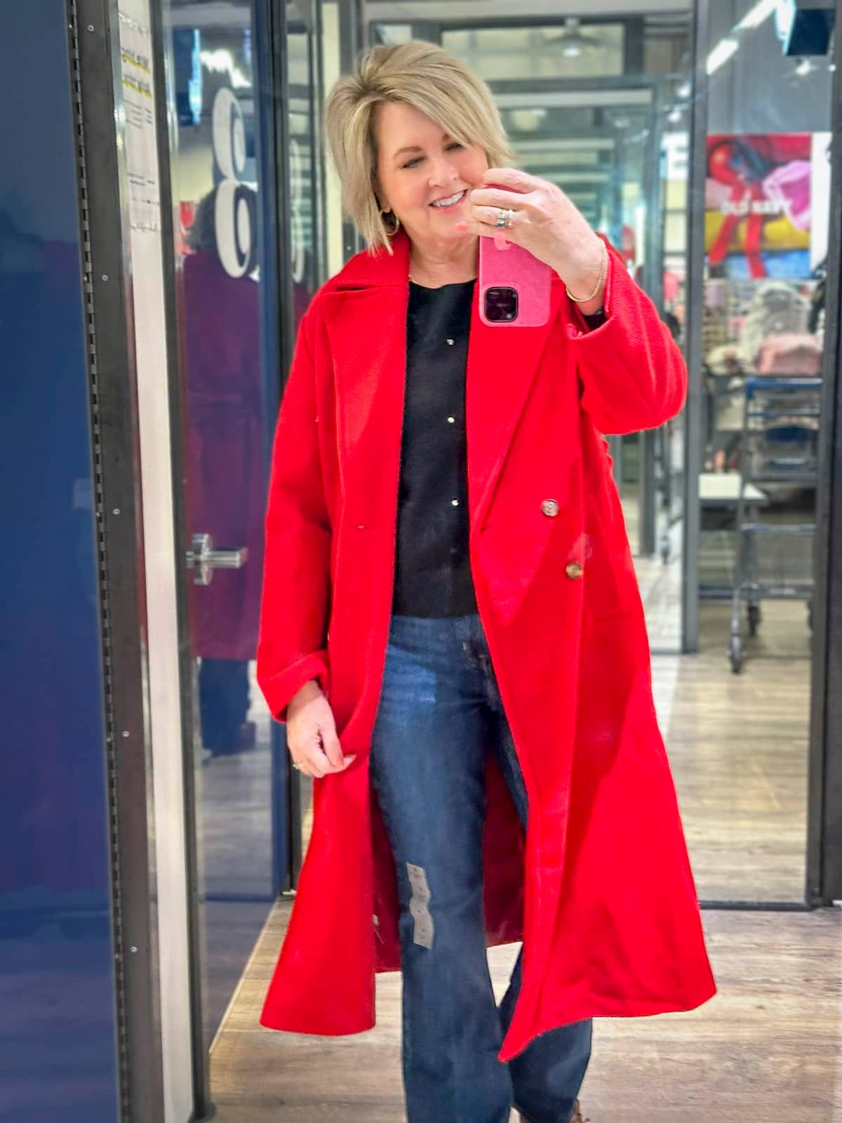 Tania Stephens wearing a black sweater, jeans, and a red coat