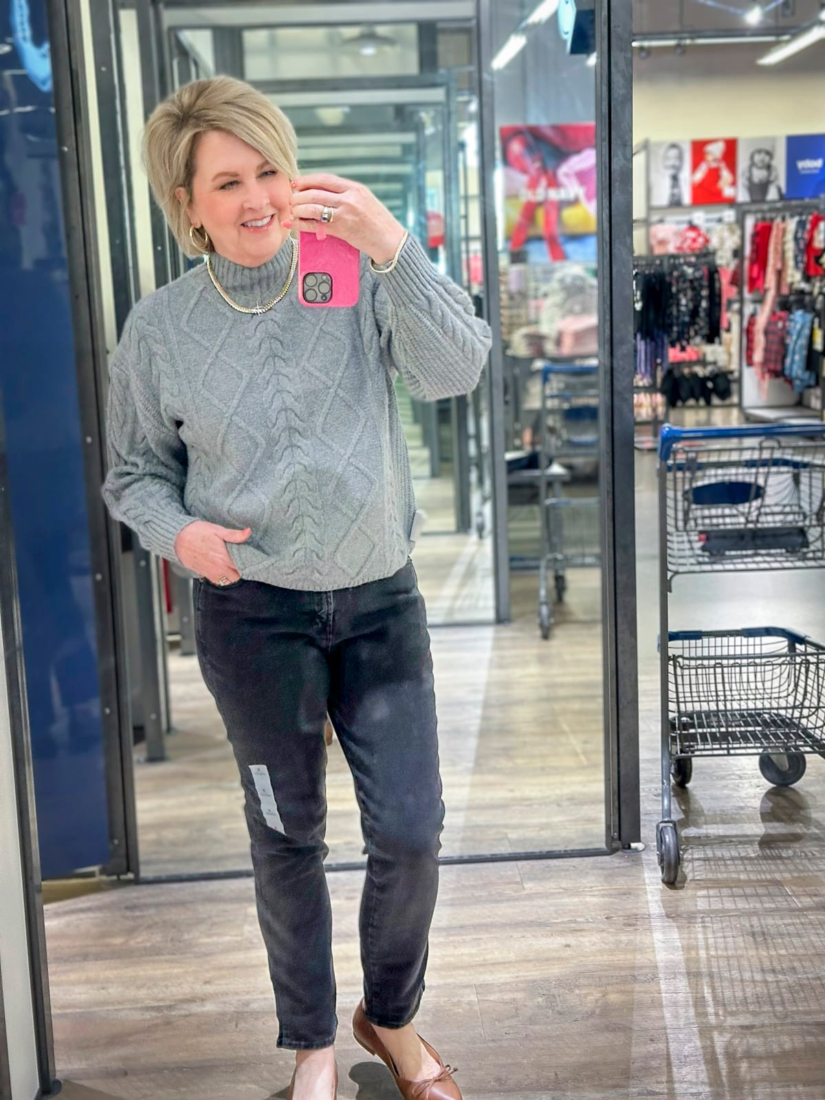 Tania is wearing a gray cable knit sweater with black pants