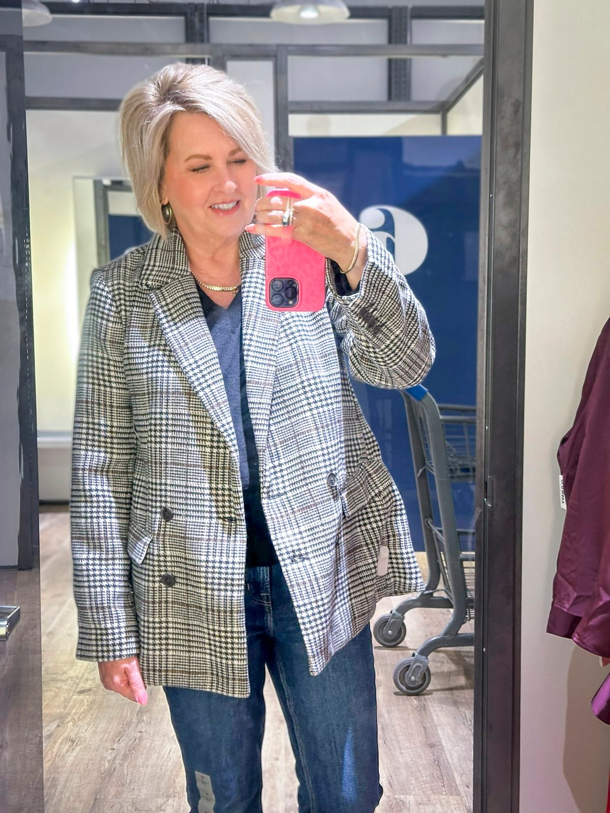 Tania is wearing a black sweater with a plaid blazer